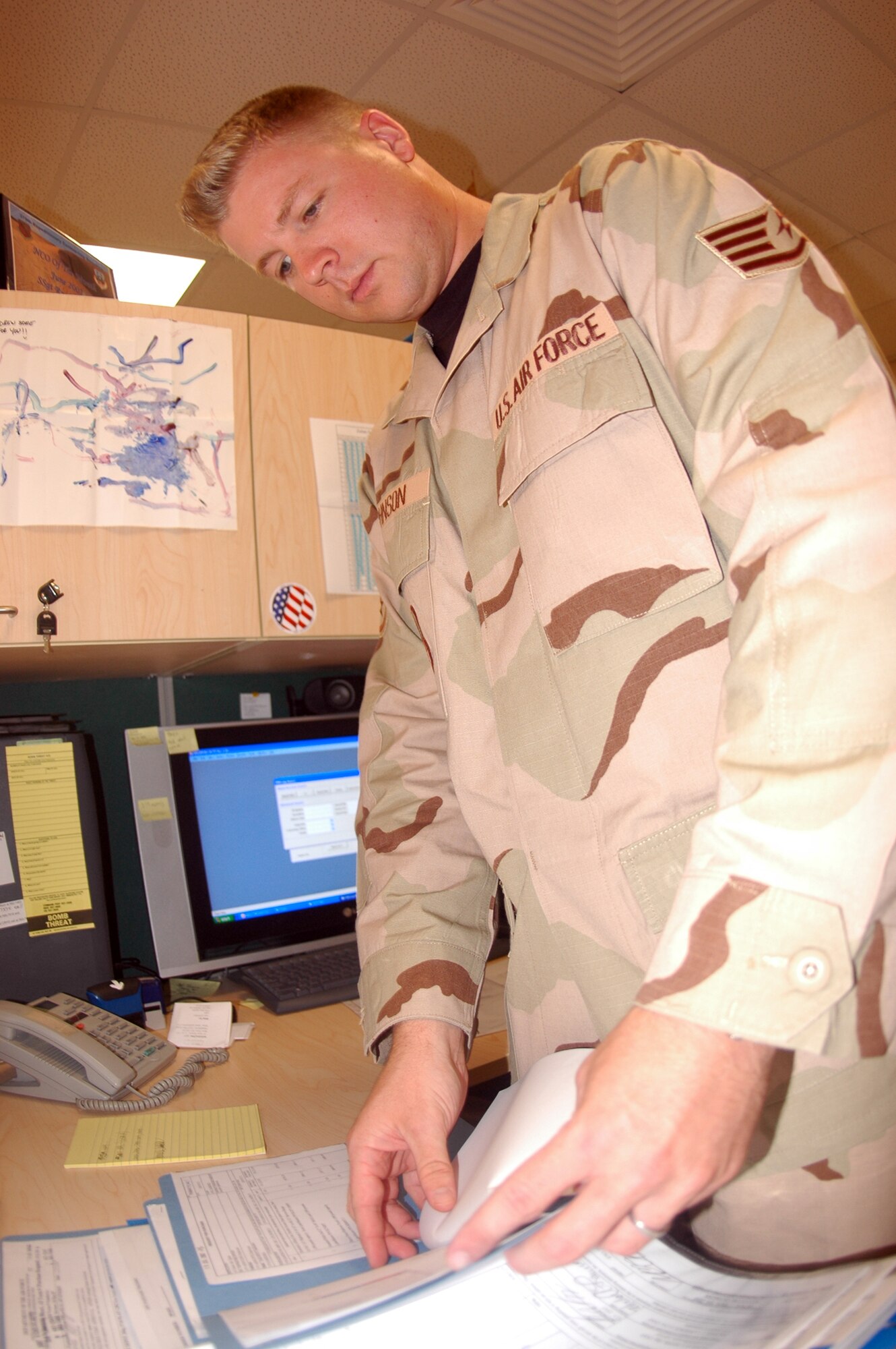 Staff Sgt. Ryan Johnson, 379th Expeditionary Contracting Squadron contingency contracting officer, looks at a Form 9 to ensure it has been completed properly. Sergeant Johnson is a native of Danville, Ill. and is deployed here from Seymour Johnson Air Force Base, N.C.(U.S. Air Force photo by Senior Airman Clark Staehle) 