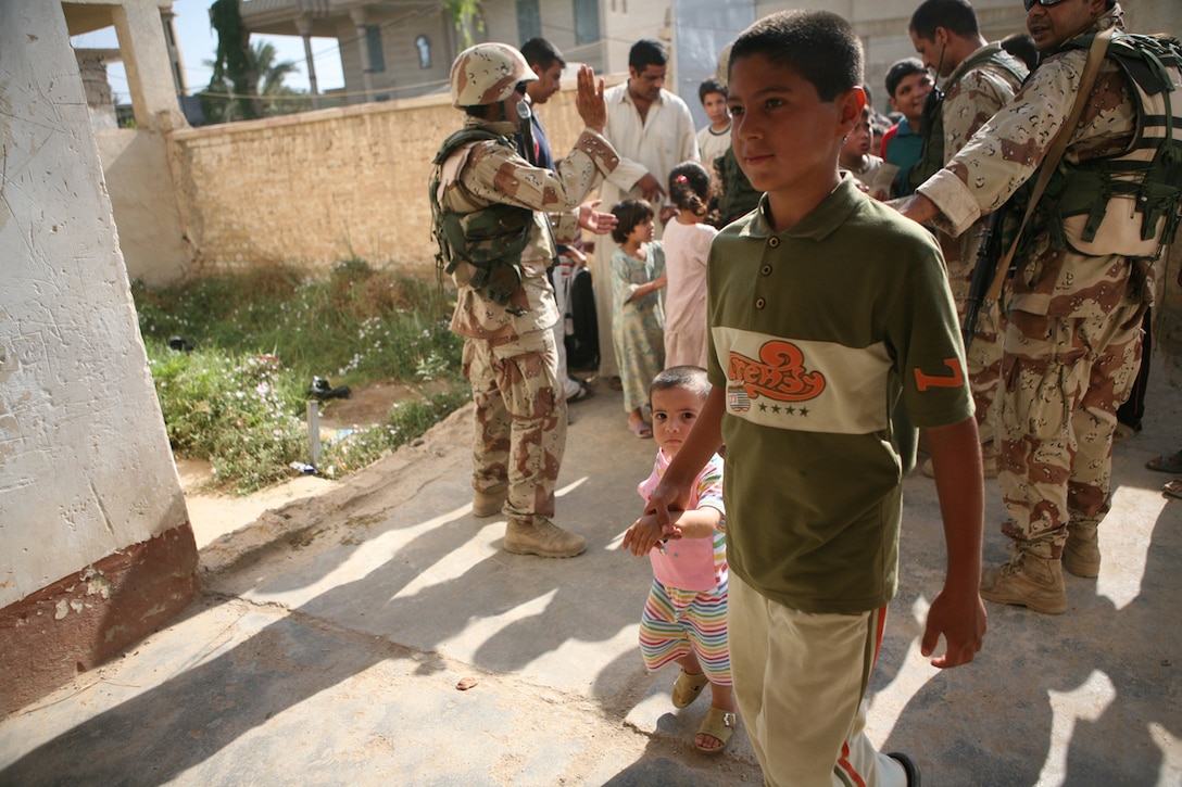 A young Iraqi boy is let into a small elementary school where Iraqi soldiers with 1st Battalion, 3rd Brigade, 1st Iraqi Army Division, were handing out gifts to the local children and engaging the local populous. The soldiers inspected report cards and talked with the children before they were allowed to make their way in. Inside the school waited more soldiers who bore greater gifts: soccer balls, pumps, stuffed animals and other toys. Operations like this introduce the local populous to the presence of the IA and are key to defeating the terror and intimidation campaign that insurgents use.