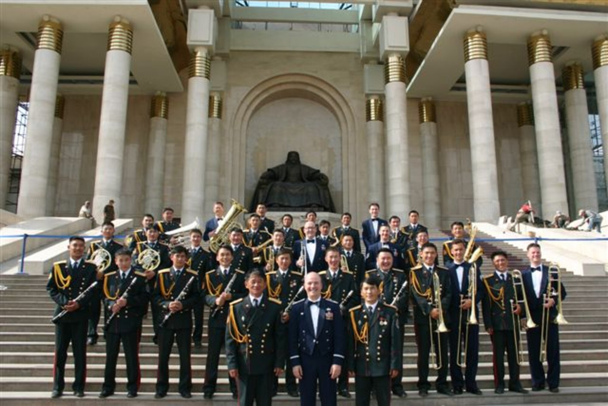 Major Matt Henry and Pacific Brass pose with members of the Mongolian Armed Forces Band outside near majestic Mongolian architecture.