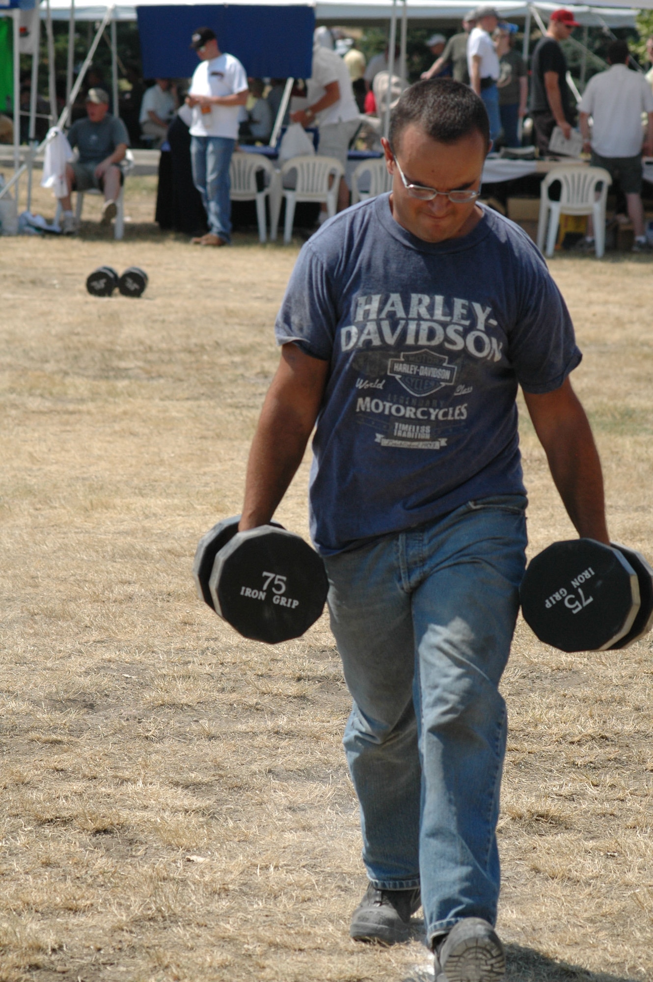 Senior Airman Pillip Amsden, 819th RED HORSE Squadron heavy equipment operator, carries two 75 pound weights in the Farmer's Walk event during the Grizzly Challenge Competition. The"Cruisin' the Summer" base picnic took place July 27, and more than 2,500 people attended the free, annual barbeque at Malmstrom Air Force Base, Mont. (U.S. Air Force photo/Airman 1st Class Dillon White).