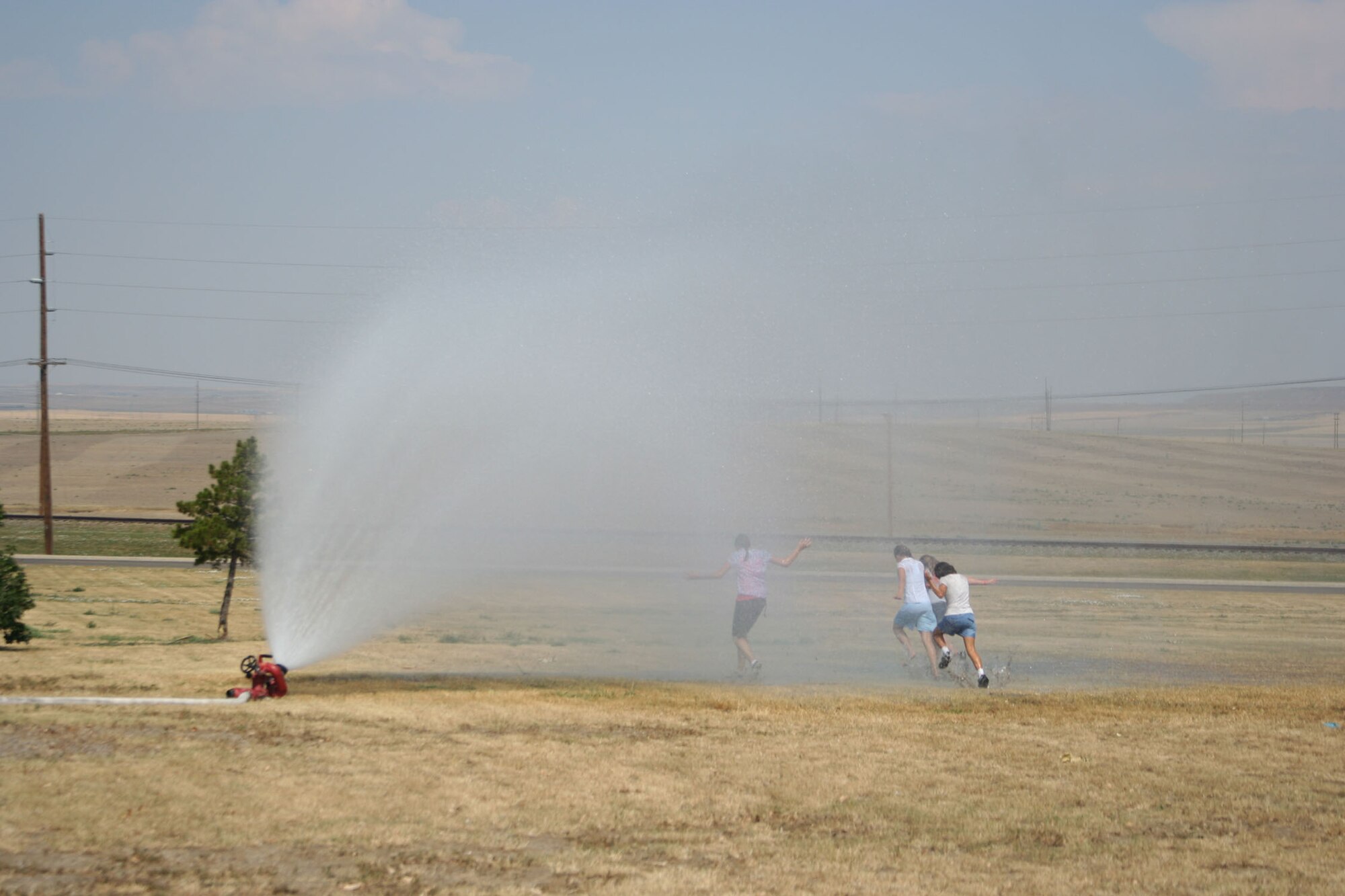 Little Warriors run under a spray of cold water supplied by the Malmstrom Air Force Base fire department during the "Cruisin' the Summer" base picnic July 27. Temperatures reached nearly 100 Fahrenheit at the event. (U.S. Air Force photo/Senior Airman Eydie Sakura).