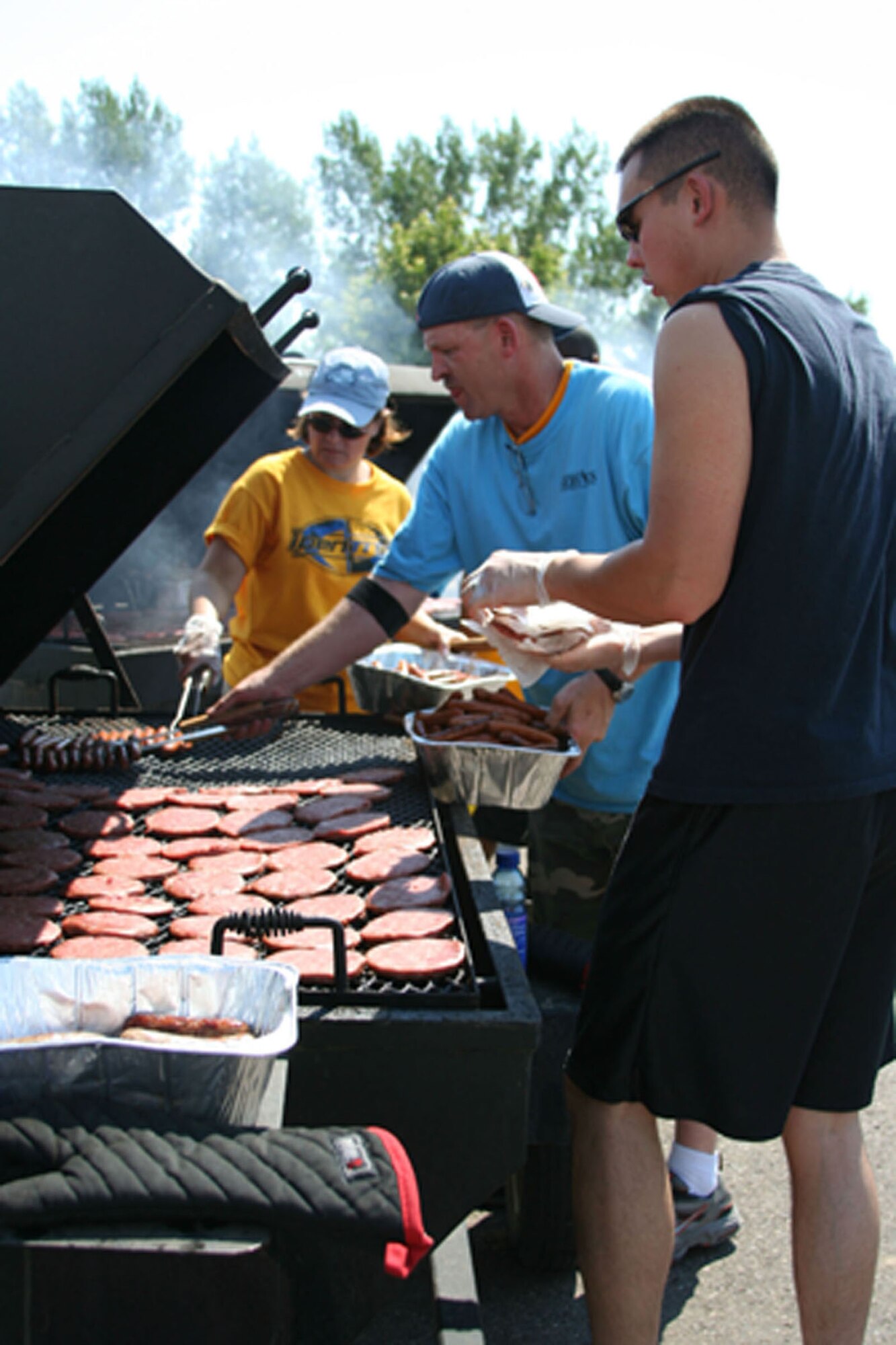 Master Sgts. Carmen Kubiak, 341st Services Squadron and Rick King, 341st Operations Group, work along side Senior Airman Neil Young, 341st Missile Maintenance Squadron, manning the hamburger grill during the "Cruisin' the Summer" base picnic July 27. (U.S. Air Force photo/Senior Airman Eydie Sakura).