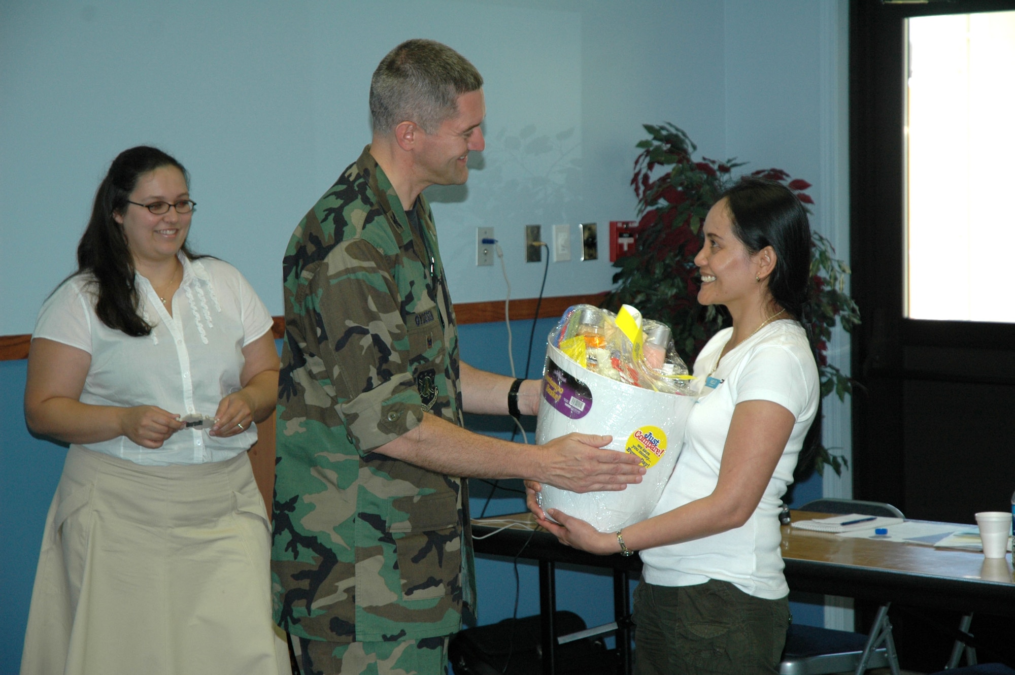 Sarah Sullivan watches Col. Paul Gydeson, 341st Space Wing vice commander, hand a care package to Merce Barrigar following a day-long Heart Link class. Heart Link teaches gives spouses an informative look into the Air Force and the supportive services Malmstrom Air Force Base provides. (U.S. Air Force photo / Airman 1st Clas Dillon White)