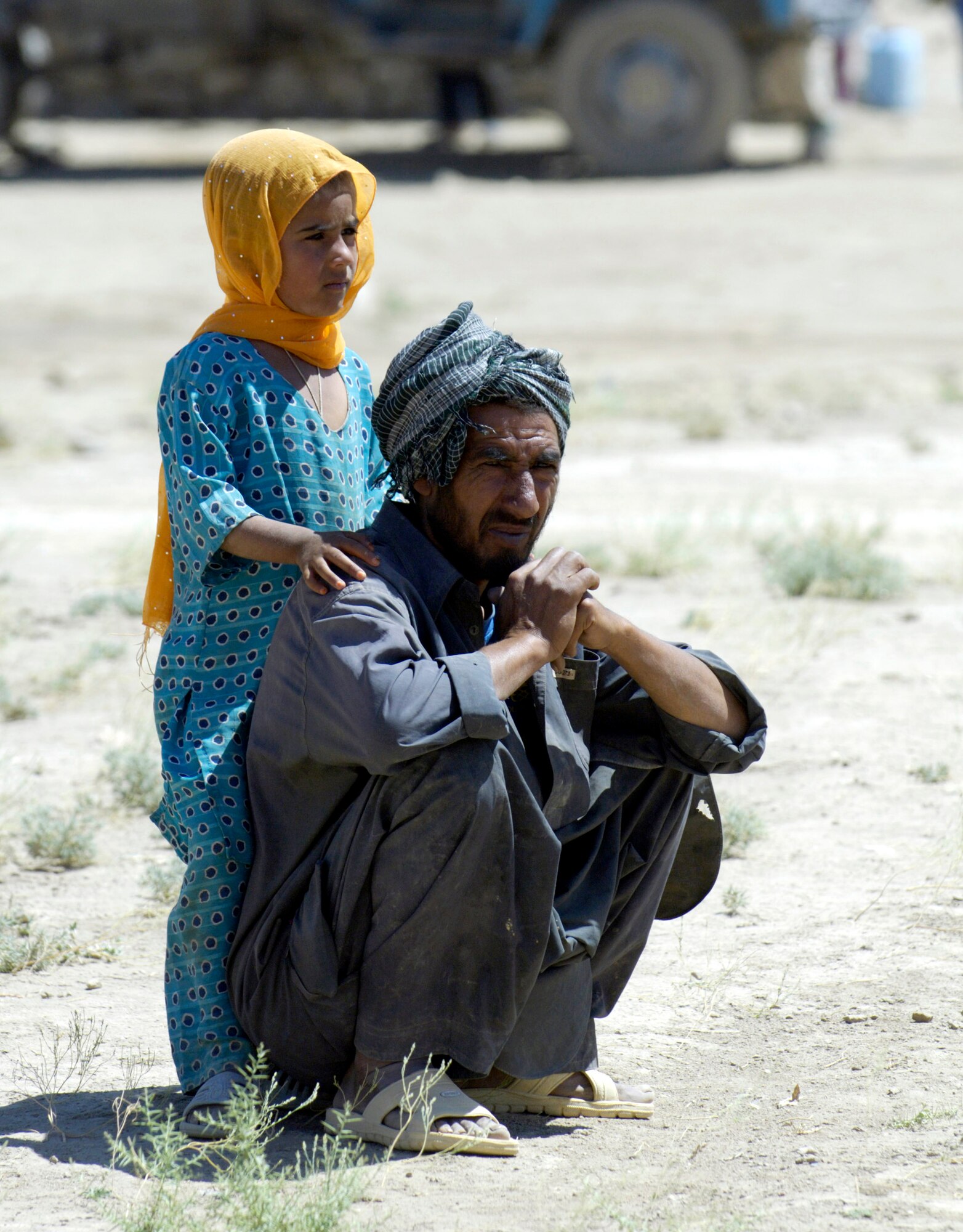 An Afghan father and his daughter watch as members of the Combined Security Transition Command-Afghanistan unload a truck full of donations from the United States after convoying July 27 to an Internal Displaced Persons camp outside of Kabul, Afghanistan. The camp is home to approximately 585 families. (U.S. Air Force photo/Master Sgt. Jim Varhegyi) 
