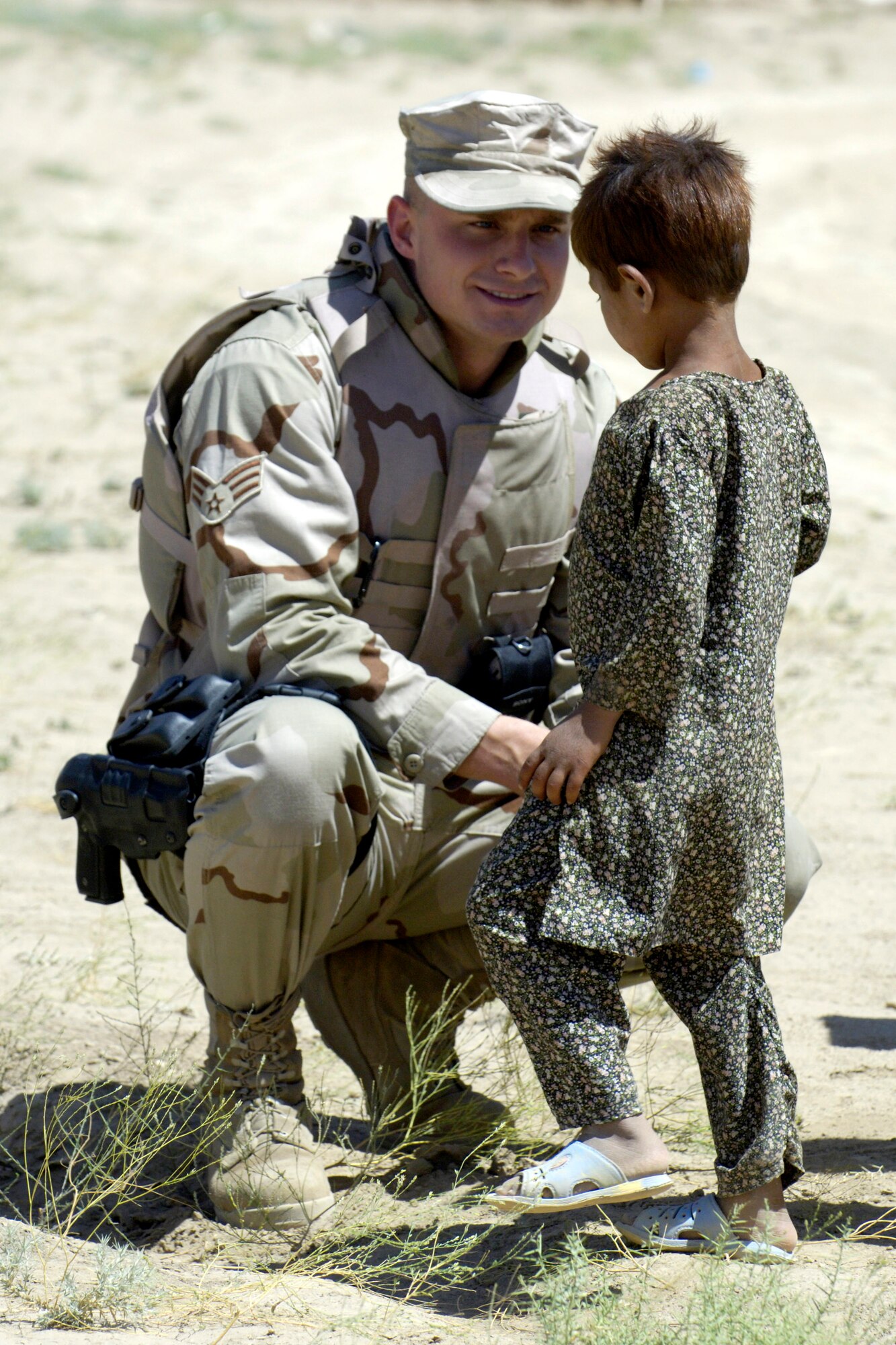 Senior Airman Andrzej Wojcicki greets an Afghan child after convoying July 27 to an Internal Displaced Persons camp outside of Kabul, Afghanistan, to deliver donations sent from the United States. Airman Wojcicki is a member of the Combined Security Transition Command-Afghanistan. (U.S. Air Force photo/Master Sgt. Jim Varhegyi) 

