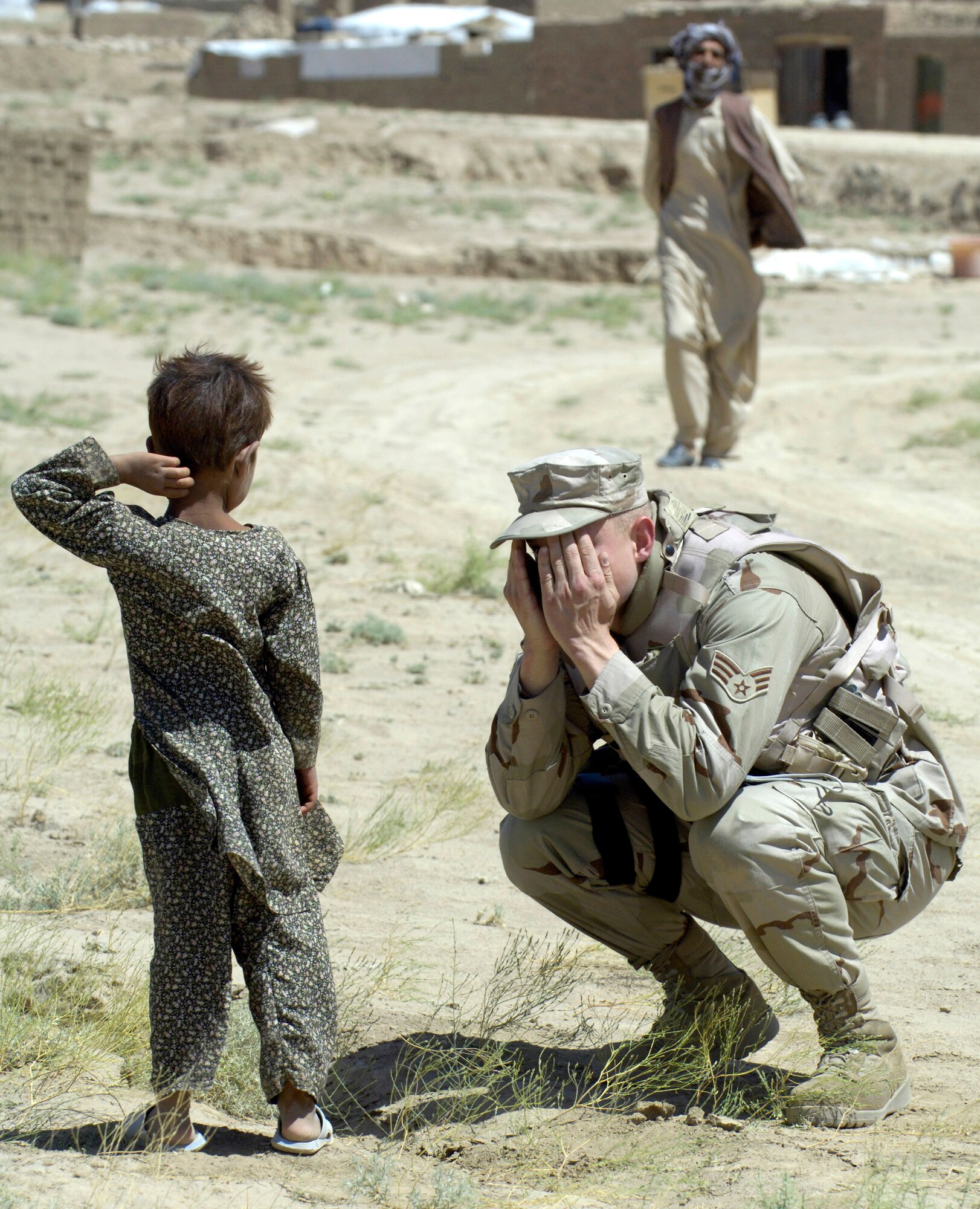 Senior Airman Andrzej Wojcicki plays peek-a-boo with an Afghan child after convoying July 27 to an Internal Displaced Persons camp outside of Kabul, Afghanistan, to deliver donations sent from the United States. Airman Wojcicki is a member of the Combined Security Transition Command-Afghanistan. (U.S. Air Force photo/Master Sgt. Jim Varhegyi) 
