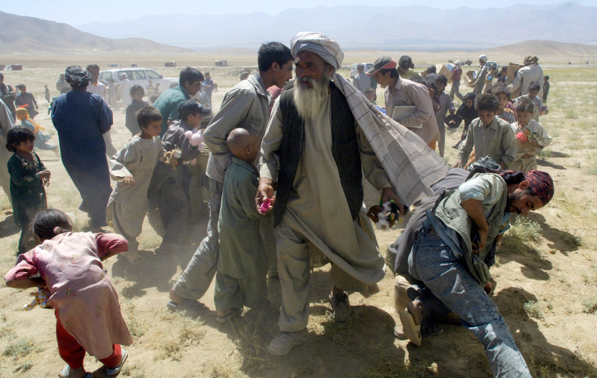 A village mullah (center) directs the dispersing of donations from the United States after members of the Combined Security Transition Command-Afghanistan convoyed July 27 to the Internal Displaced Persons camp outside of Kabul, Afghanistan, to deliver the donations. (U.S. Air Force photo/Master Sgt. Jim Varhegyi) 