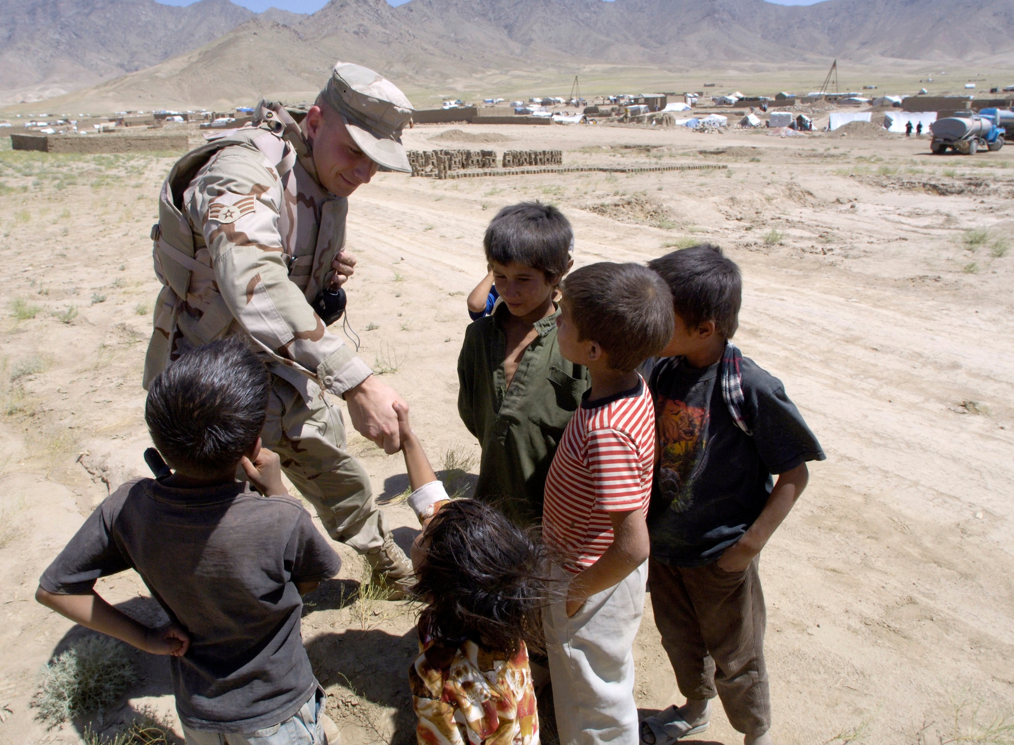 Senior Airman Andrzej Wojcicki greets a group of children after convoying July 27  to an Internal Displaced Persons camp outside of Kabul, Afghanistan, to deliver donations sent from the United States. Airman Wojcicki is a member of the Combined Security Transition Command-Afghanistan. (U.S. Air Force photo/Master Sgt. Jim Varhegyi) 
