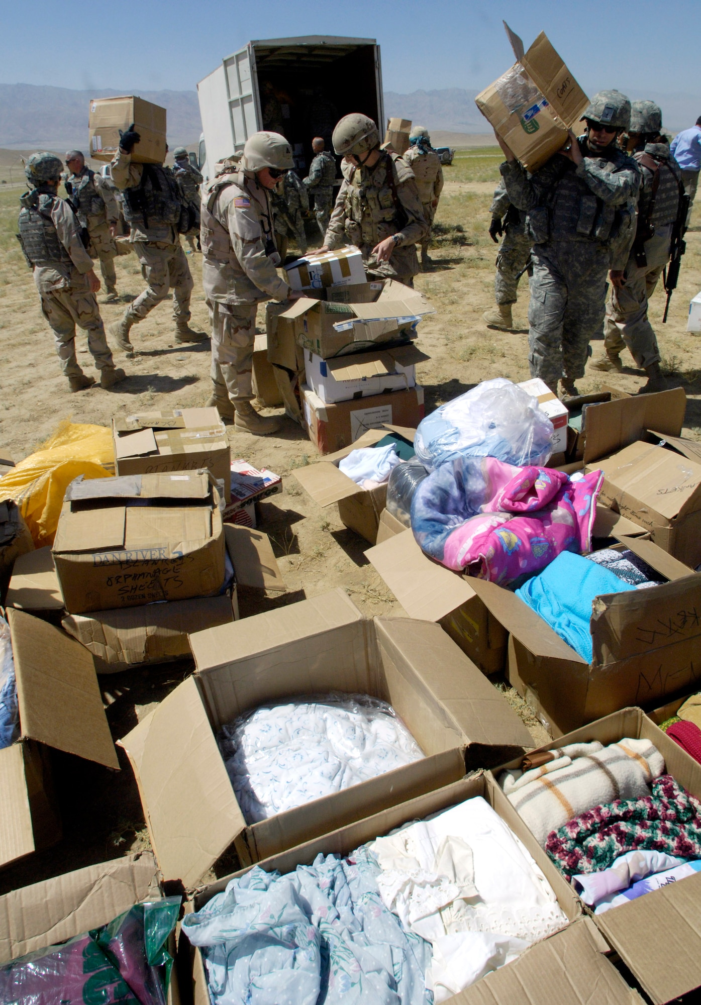 Members of the Combined Security Transition Command-Afghanistan unload a truck full of donations from the United States after convoying July 27 to an Internal Displaced Persons camp outside of Kabul, Afghanistan. The camp is home to approximately 585 families. (U.S. Air Force photo/Master Sgt. Jim Varhegyi) 
