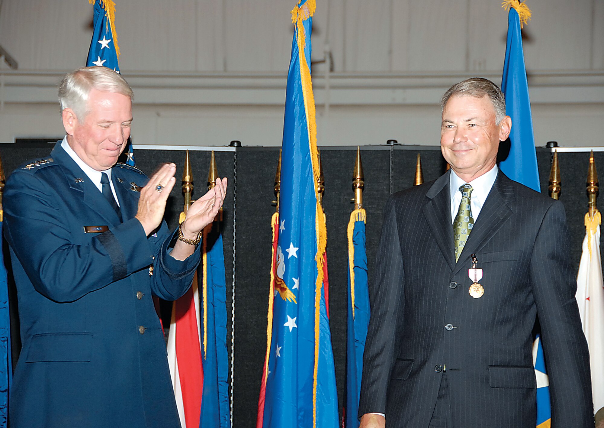 Gen. William Looney, the Air Education and Training Command commander at Randolph Air Force Base, Texas, applauds after pinning an Outstanding Civilian Career Service Award medal on the lapel of Robert May, the ASC executive director. Mr. May retired from federal service July 24 during a formal ceremony at the National Museum of the U.S. Air Force. Gen. Looney was the Aeronautical Systems Center’s former commander. (Air Force photo by Christy Webb)