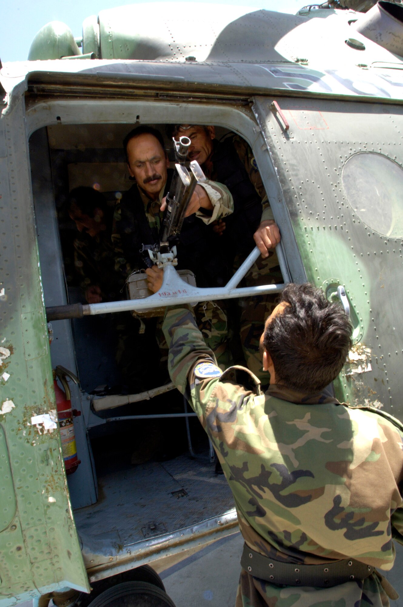 Helicopter crewmen from the Afghan National Army air corps mount a door gun on their MI-17 helicopter prior to a mission July 25 at Kabul International Airport in Afghanistan. U.S. Air Force members act as mentors to the ANA soldiers and are assigned to the Combined Security Transition Command-Afghanistan with headquarters on Camp Eggers in  Kabul.  (U.S. Air Force photo/Master Sgt. Jim Varhegyi)