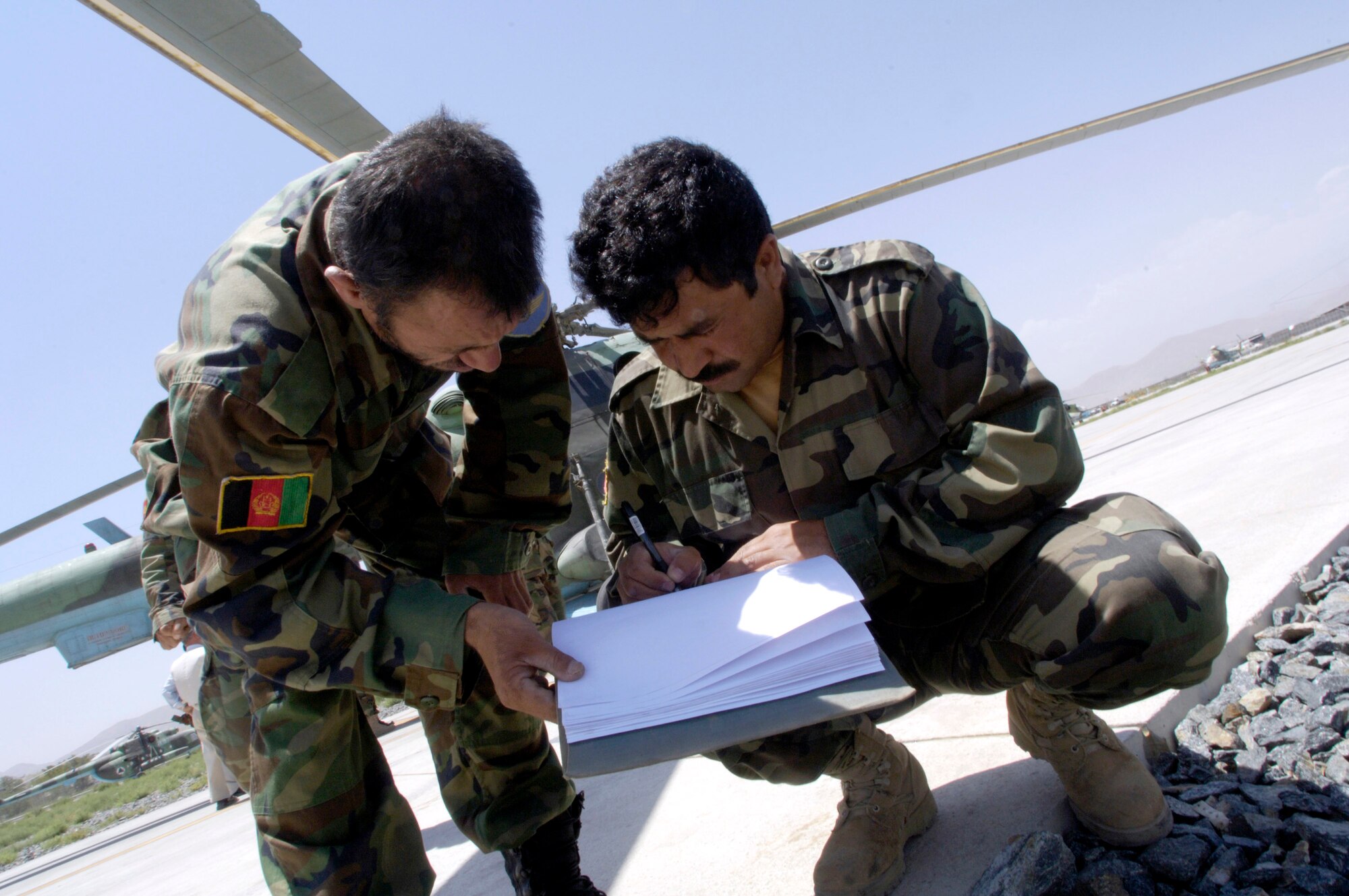 Helicopter maintainers from the Afghan National Army air corps check over the maintenance records for an MI-17 helicopter before a mission July 25 at Kabul International Airport in Afghanistan. U.S. Air Force members act as mentors to the ANA soldiers and are assigned to the Combined Security Transition Command-Afghanistan headquartered on Camp Eggers, Kabul, Afghanistan. (U.S. Air Force photo/Master Sgt. Jim Varhegyi)