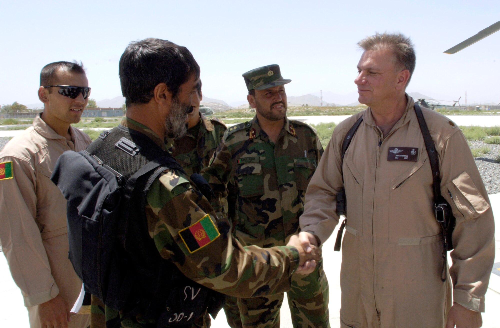Maj. Mark Campbell greets the commanding pilot of an MI-17 helicopter flight crew from the Afghan National Army air corps prior to a mission July 25 at Kabul International Airport in Afghanistan. Major Campbell, an Air Force mentor, is assigned to the Combined Security Transition Command-Afghanistan with headquarters on Camp Eggers, Kabul, Afghanistan. (U.S. Air Force photo/Master Sgt. Jim Varhegyi)