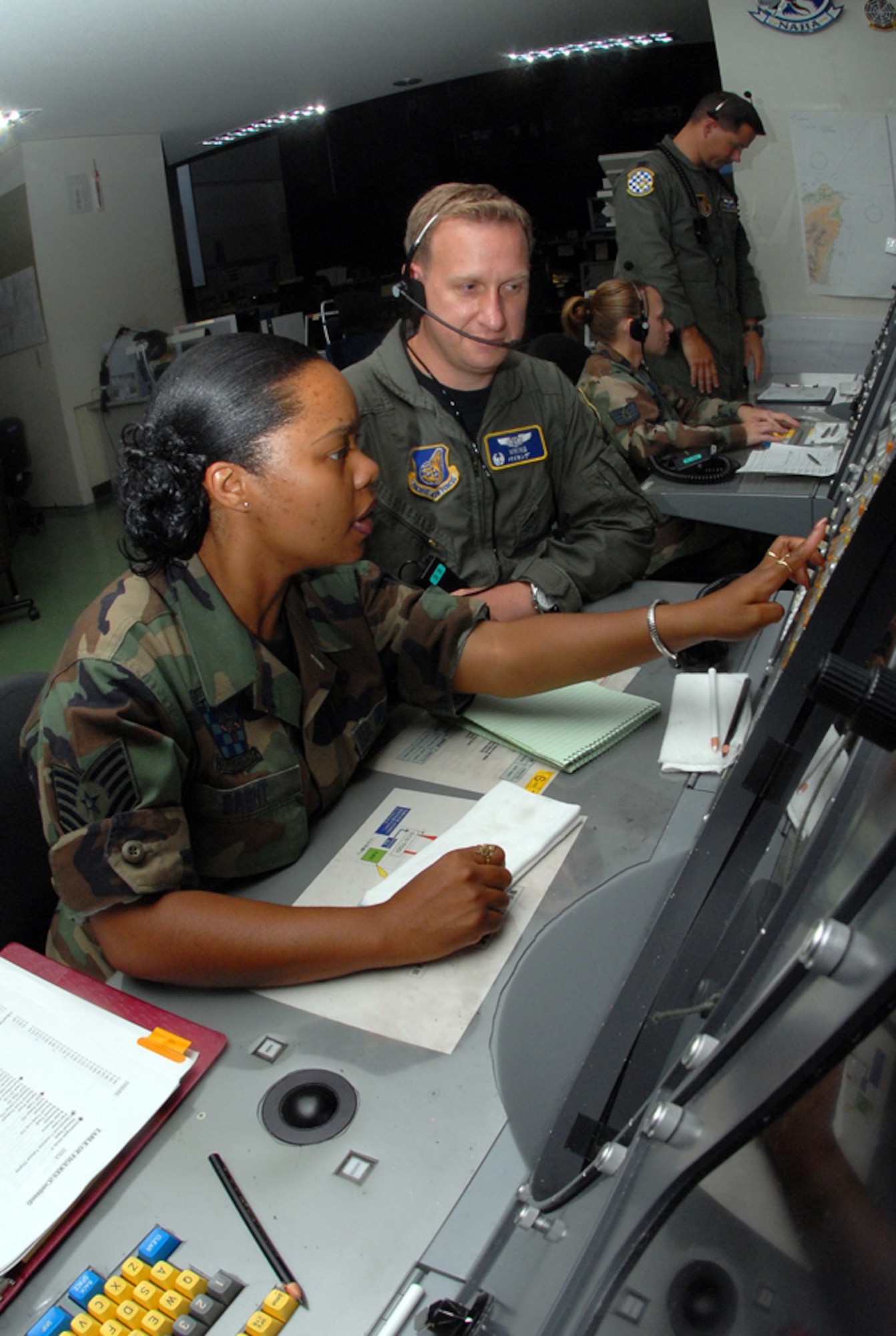 Tech. Sgt. Connie Brent (left) and Maj. Charles Dennison, both with the 623rd Air Control Flight, control ae Large Force Exercise (LFE) by using the Base Air Defense Ground Environment system. Sergeant Brent relays time- sensitive information to Maj. Dennison, the mission crew commander, where he controls the air space by guiding aircraft into different sections according to the mission plan.  U.S. Air Force photo/Staff Sgt. Steven Nabor