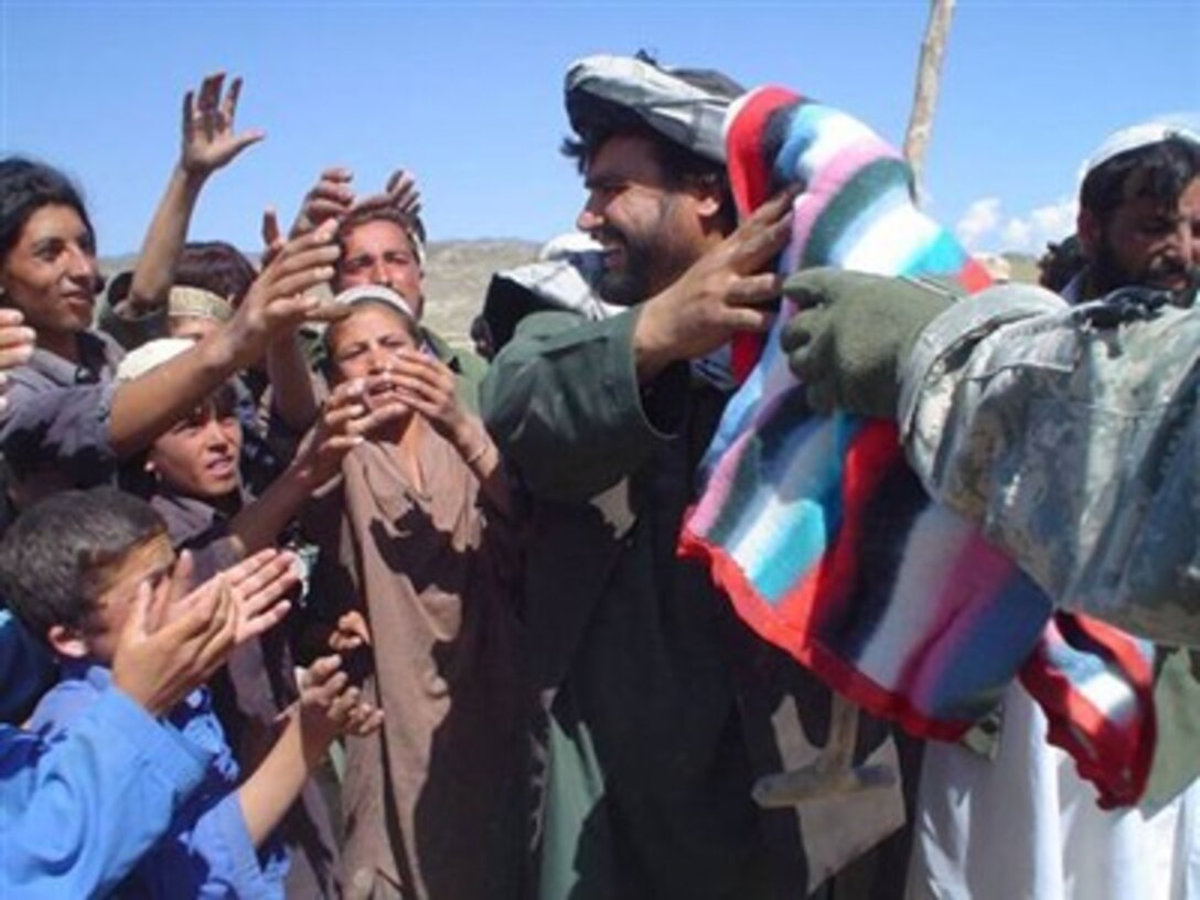 A U.S. Army soldier passes humanitarian aid items to Muhammed Moabem, Orgun-E sub-governor for distribution to the residents of Tarmirah village, Afghanistan, on July 10, 2007.  Soldiers from Task Force Pacemaker provided the comfort items.  