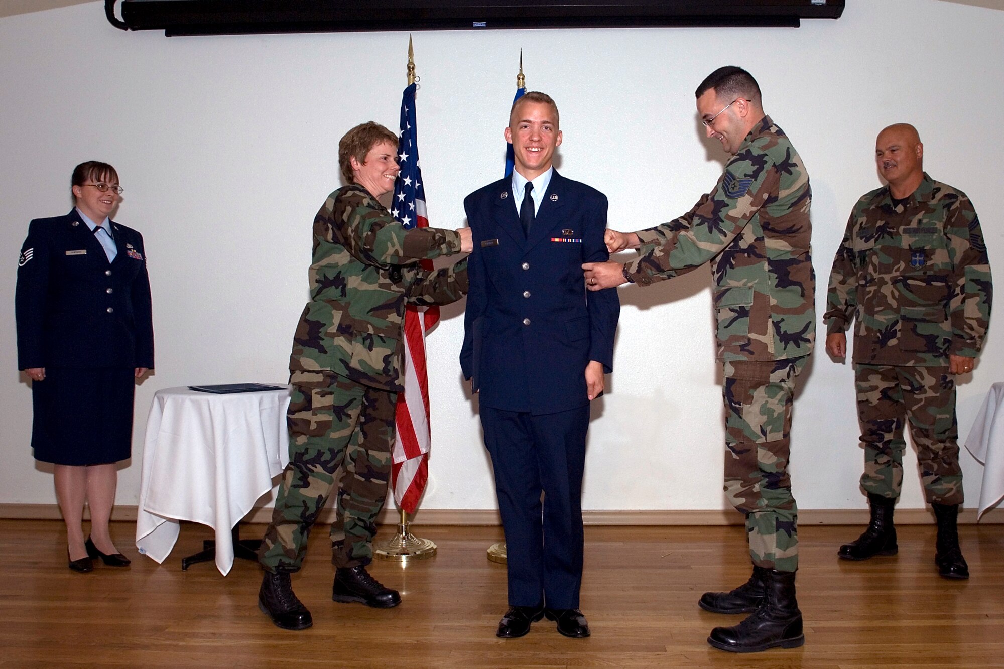 Col. Nancy Wharton (left), 95th Air Base Wing vice commander, and Tech. Sgt. Jess Houk (right), 95th Comptroller Squadron wing resource advisor, tack the rank of senior airman onto Colby Corbett, also with the Comptroller Squadron, during the Team Edwards promotion ceremony at Club Muroc on July 27. The ceremony was in honor of Edwards' enlisted promotees for the month of August. (Photo by Edward Cannon)
