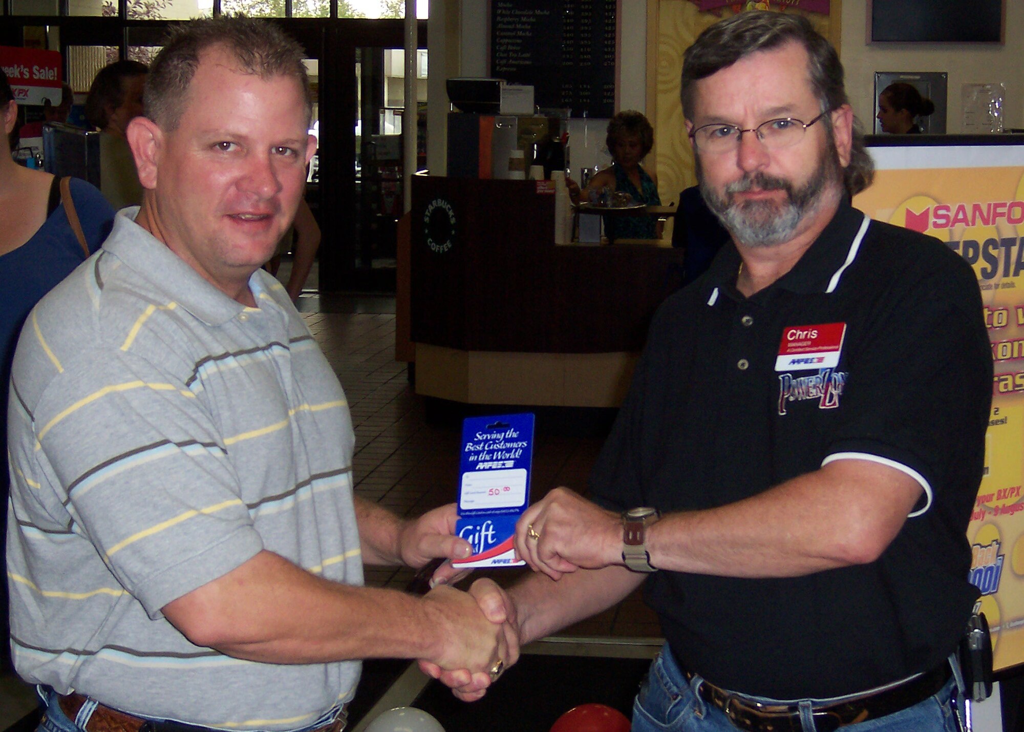 EIELSON AIR FORCE BASE, Alaska--Chris Redmond, BX assistant manager, presents a $50 gift card to the day?s 112th customer. (Photo by Florence Scott)