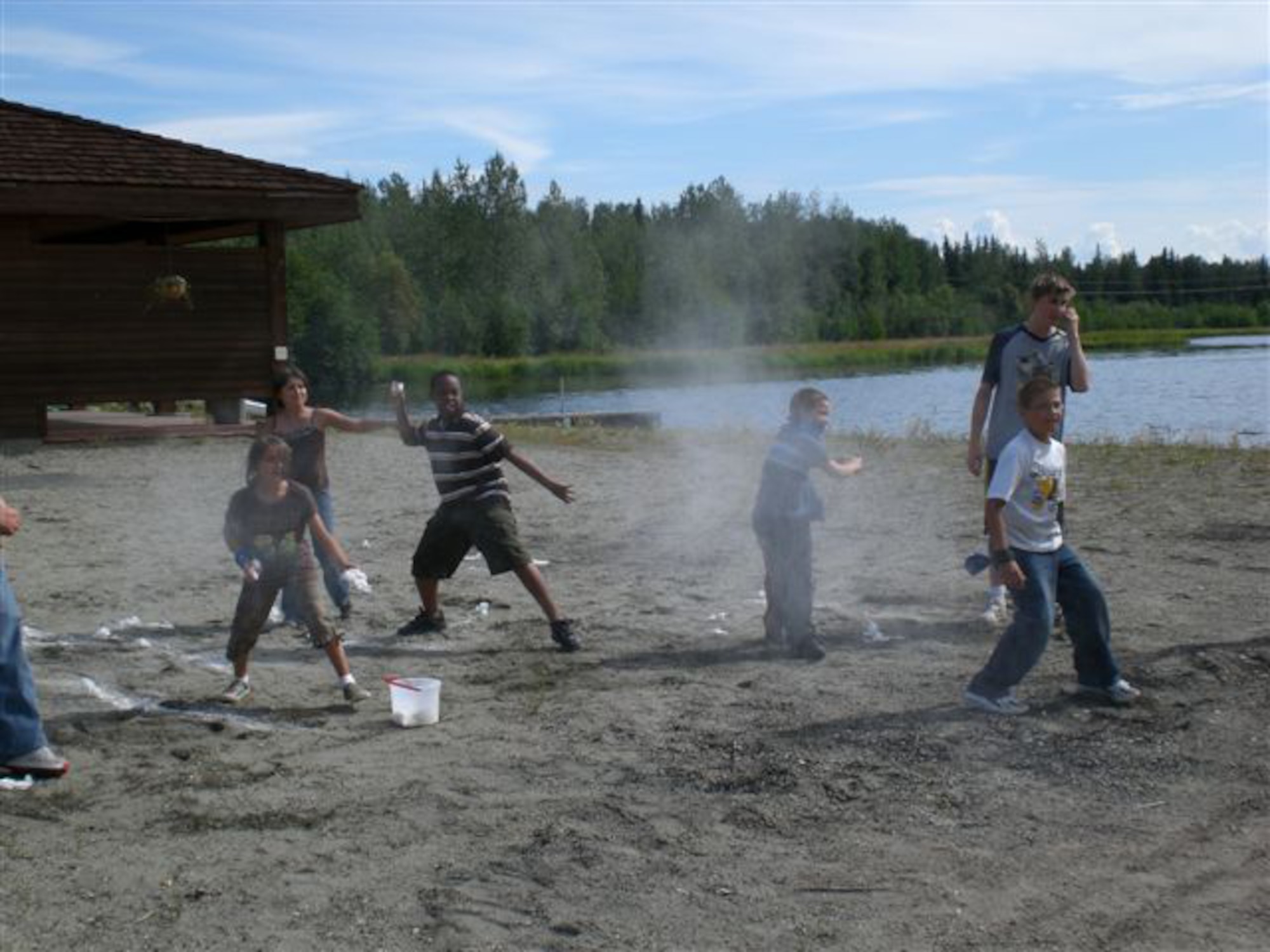 EIELSON AIR FORCE BASE, Alaska--Xavier Withers (middle) throws a flour grenade with fellow Team Blue team mates at opposing team, Team Orange, July 18 at Bear Island during a Survivor Challenge game set up for Eielson youth. The game was modeled after the reality television show, and competetors were challenged against the other team for immunity in a series of physical and mental challenges. (photo by Misty Campbell)