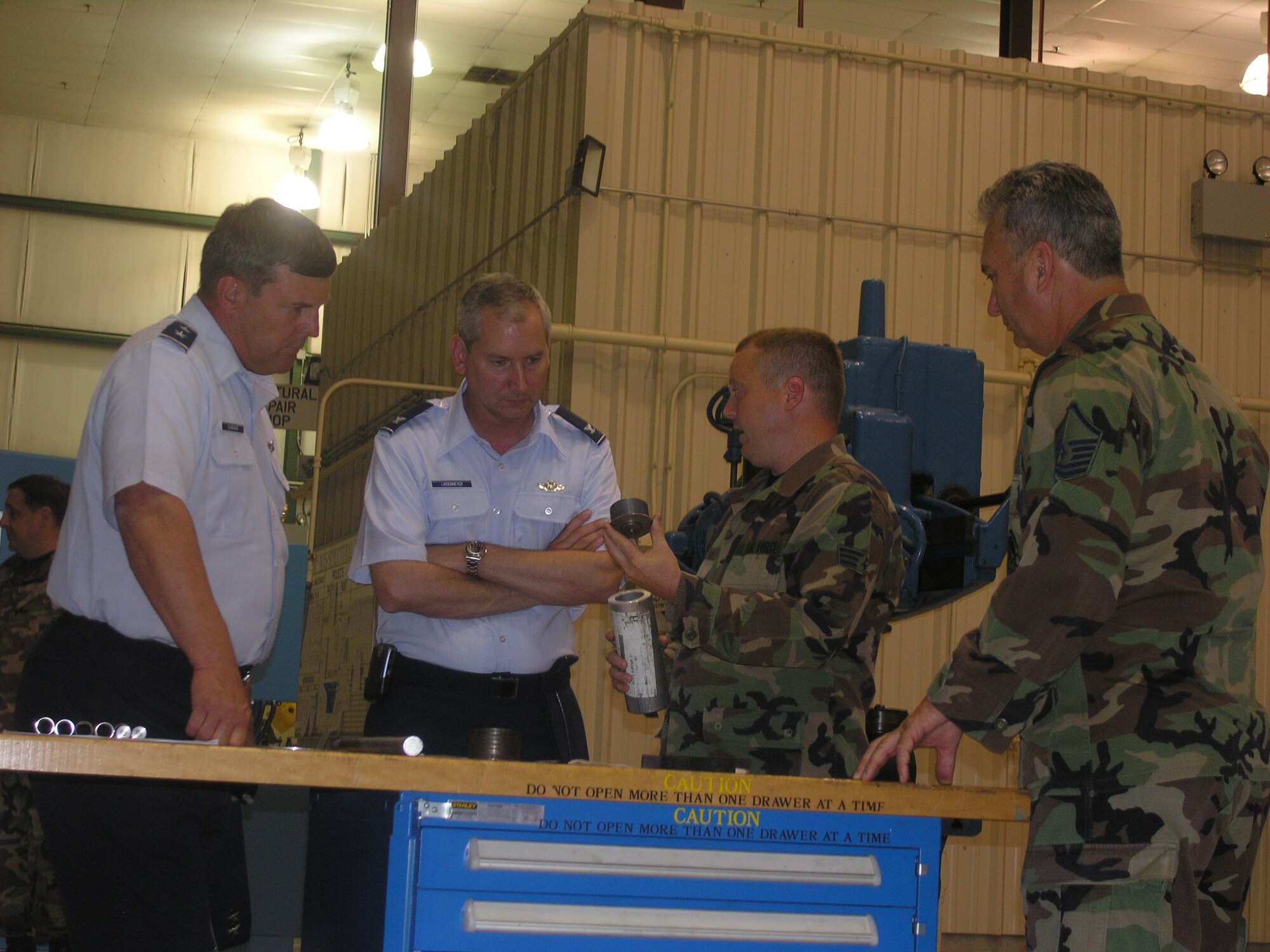 Senior Airman Jamie Mozingo (center right) explains to  4th Air Force Commander Maj. Gen. Robert (far left) and Col. Fritz Linsenmeyer (center left), new wing commander for the 916th Air Refueling Wing, how the maintenance shop makes aircraft nose wheel protectors. Master Sgt. Dave Theriot (far right) listens as well. Maj. Gen. Duignan was at Seymour Johnson Air Force Base in mid-July to help welcome Col. Linsenmeyer during an official change of command ceremony.