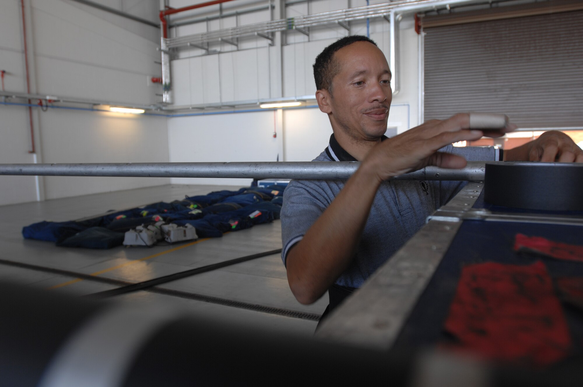 Tops In Blue vocalist Tech. Sgt. Keith Martin Sr., who also serves as a wardrobe assistant, rigs clothes racks during set-up for the RAF Mildenhall show, July 24, 2007. The team functions as a self-contained unit handling all wardrobe, transportation, airlift, lodging, dining, palletizing, etc., throughout the entire tour. (U.S. Air Force photo by Tech. Sgt. Tracy L. DeMarco)