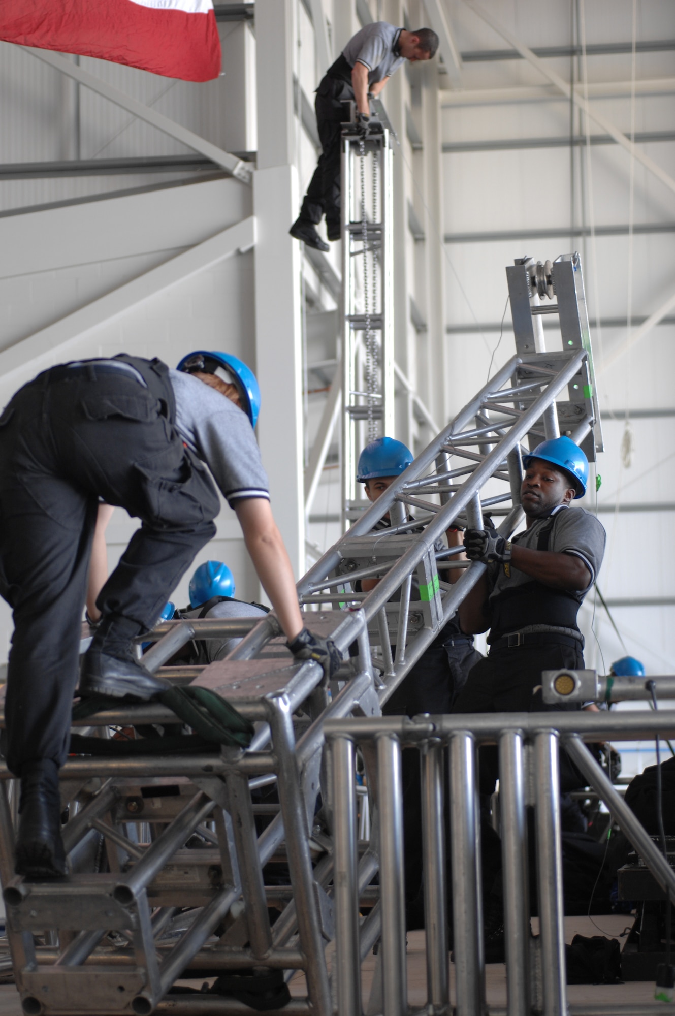 In preparation for the RAF Mildenhall show, Staff Sgt. Kevin Guy, the drummer for the 2007 Tops In Blue team, lifts tower 2 of the stage set-up with the help of other members from the performance team, July 24, 2007. The day before every show the Tops In Blue performing team, with guidance from five technical personnel, sets up more than 54,000 pounds of staging, lighting, audio, and special effects equipment. (U.S. Air Force photo by Tech. Sgt. Tracy L. DeMarco)