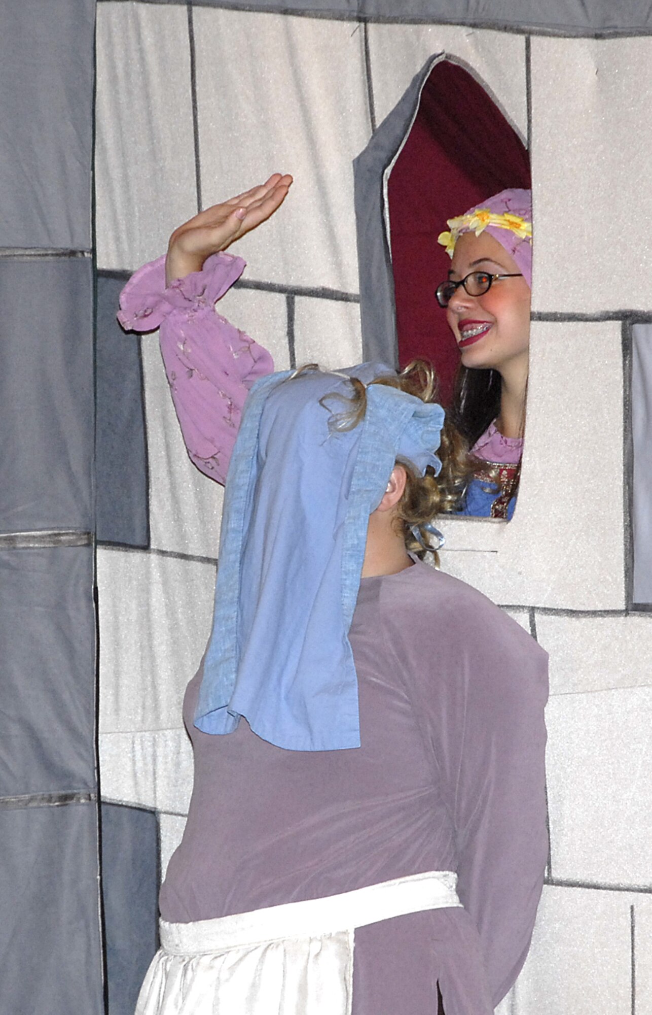 Maid Marion, played Laura Gilman, waves to passers by, while Marion's Maid, played by Dakota Simpson, hides in plain sight at the Missoula Children's Theater production of Robin Hood July 27 at the Commumity Activity Center. (U.S. Air Force photo/Harry Tonemah)