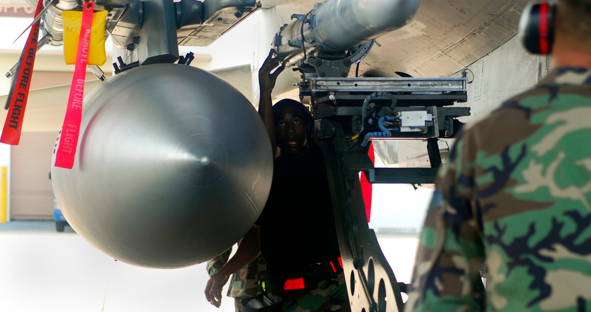Staff Sgt. Alfred Agee guides a missile to be loaded on the aircraft weapons station as the evaluator looks on during the Weapons Load Crew of the Quarter competition held here July 20. Sergeant Agee is assigned to the 18th Aircraft Maintenance Squadron, 67th Aircraft Maintenance Unit. (U.S. Air Force photo/Airman 1st Class Sheila deVera) 
