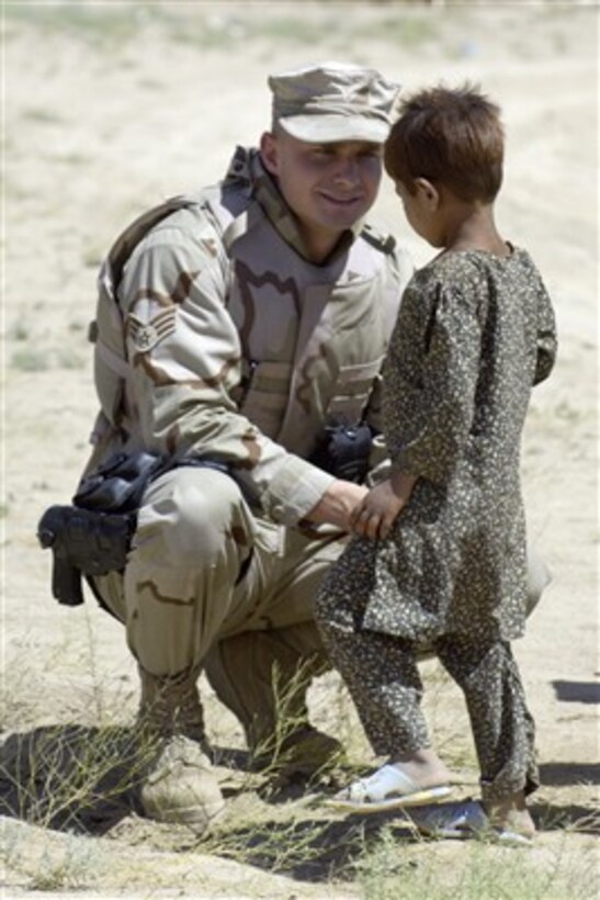 U.S. Air Force Senior Airman Andrzej Wojcicki talks to an Afghan child at an internal displaced persons camp outside of Kabul, Afghanistan, on July 27, 2007.  Wojcicki, and other members of the Combined Security Transition Command-Afghanistan, gather every two weeks to deliver clothing, toys, school supplies and toiletries sent from the United States to the needy in the Kabul area.   