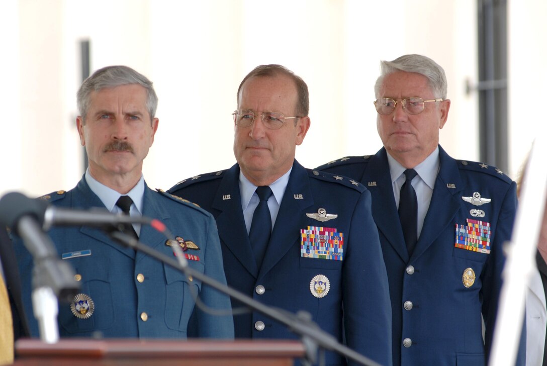 Maj Gen Brett Cairns, Maj. Gen Hank Morrow, and Maj Gen. Doug Burnett stand as Ms Gina Hamilton sings God Bless America during the ribbon cutting ceremony for America's AOC.