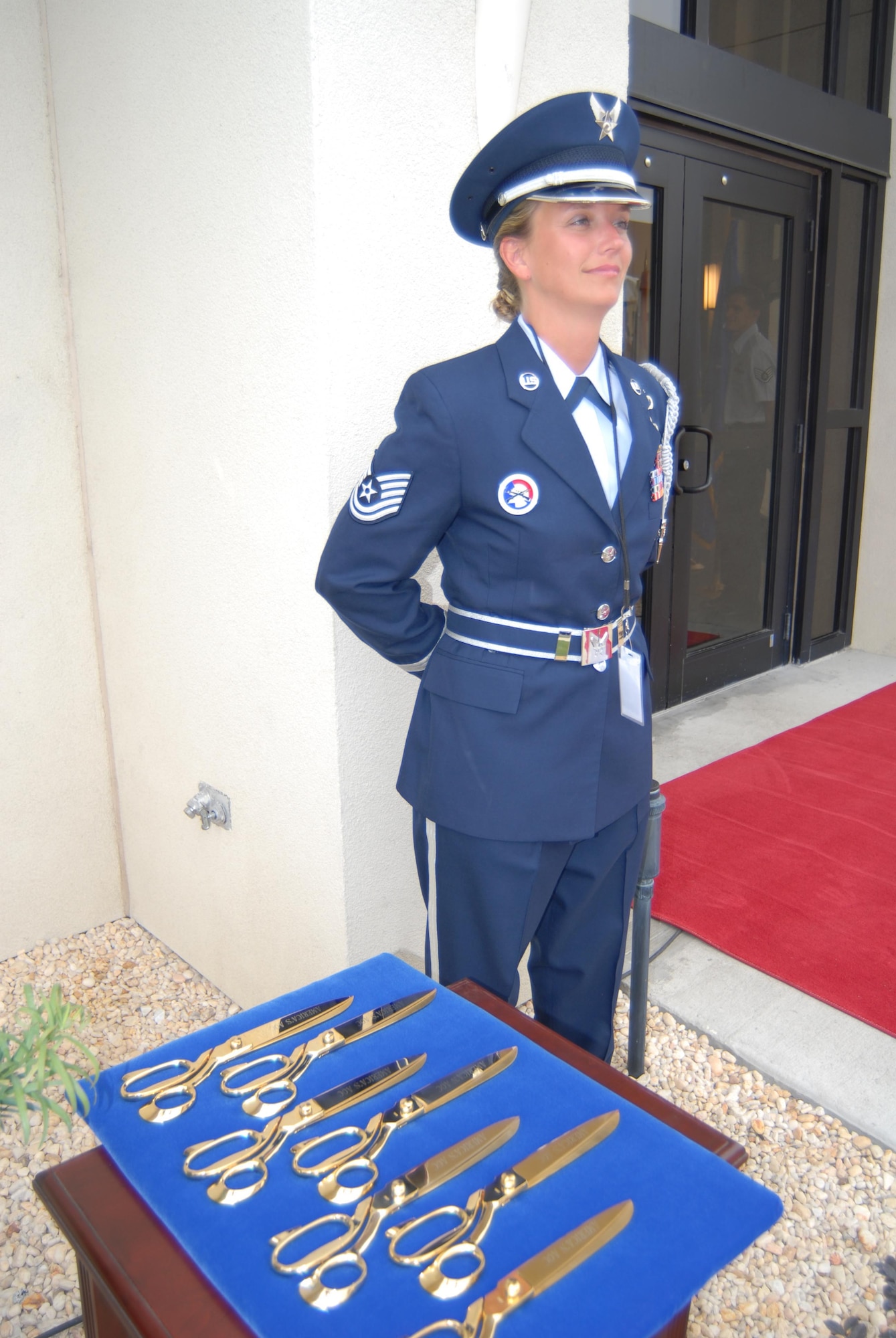 Honor Guard member Technical Sergeant Tiffany Kellum stands guard over the golden scissors used to cut the ribbon at the grand opening of "America's AOC".