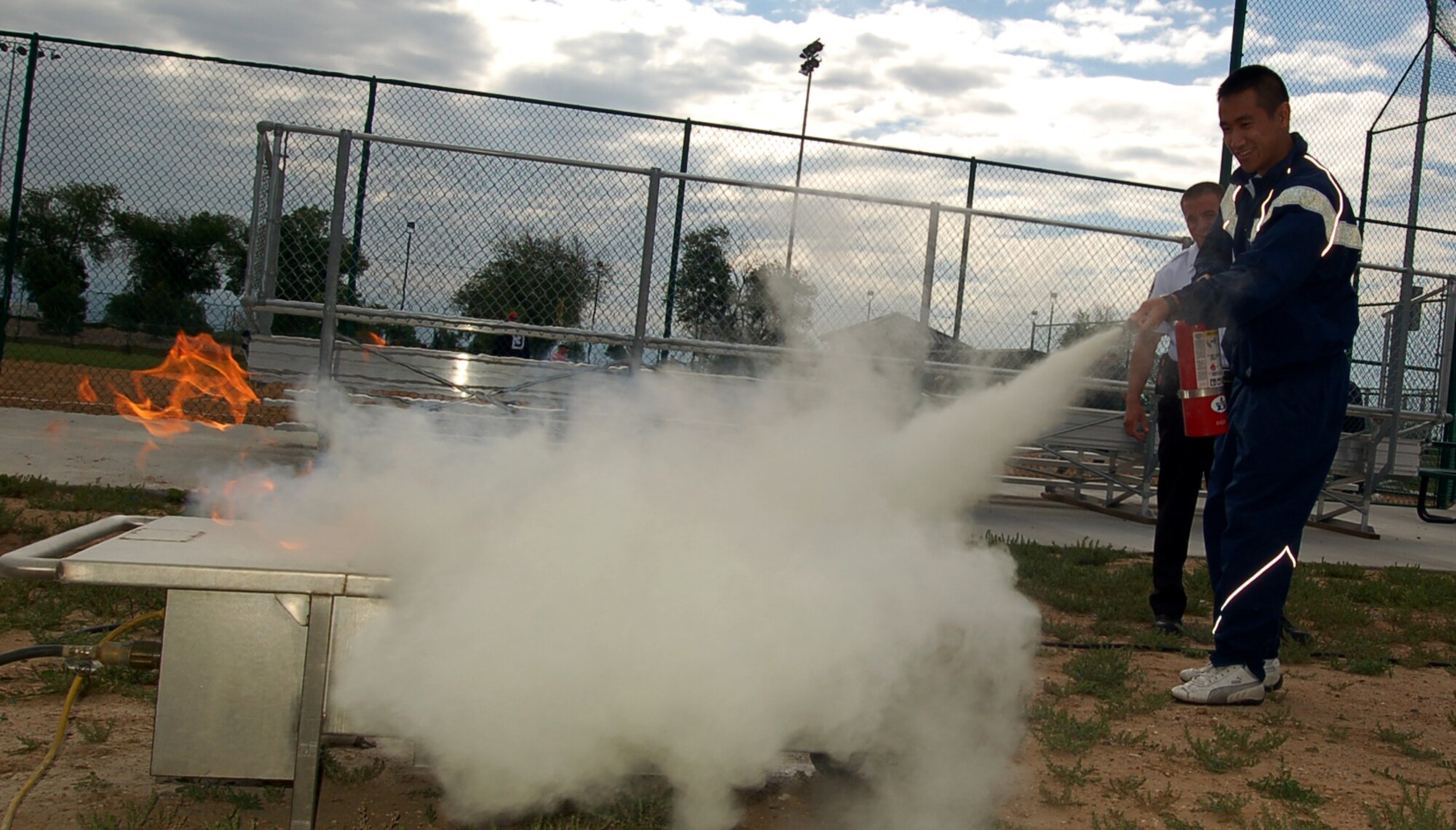 BUCKLEY AIR FORCE BASE, Colo. -- Airman Jonathan Vu, from Det. 45, puts out a controlled fire with an extinguisher at the Buckley Sports, Field and Safety Day June 1. The fire department's fire extinguisher training demonstration was just one of many booths and demos that offered safety tips to Buckley members. (U.S. Air Force photo by Senior Airman Jacque Lickteig)