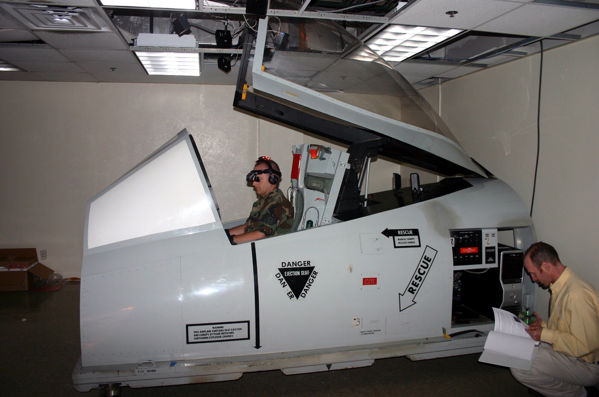 While Tech. Sgt. Jason Groth, 363rd Training Squadron, prepares to demonstrate the Generalized Operations Simulation Environment program installed in this A-10 cockpit model, Southwest Reasearch Institute senior research analyst Malachi Weirpts inspects the GOSE software. (U.S. Air Force photo/Staff Sgt. Tonnette Thompson)