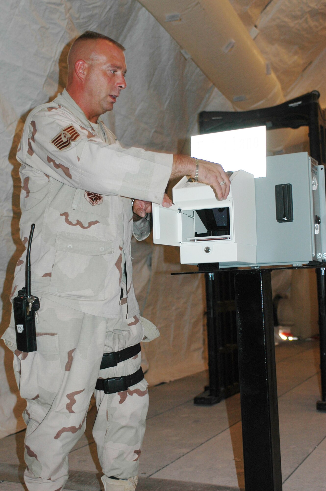Tech. Sgt. Steve Neith demonstrates how a handprint scanner will work once the new Defense Biometric Identification Database System is complete in Southwest Asia. It is expected to become operational here around June 15. Sergeant Neith is assigned to the 379th Expeditionary Security Forces Squadron. (U.S. Air Force photo/Staff Sgt. Cassandra Locke)
