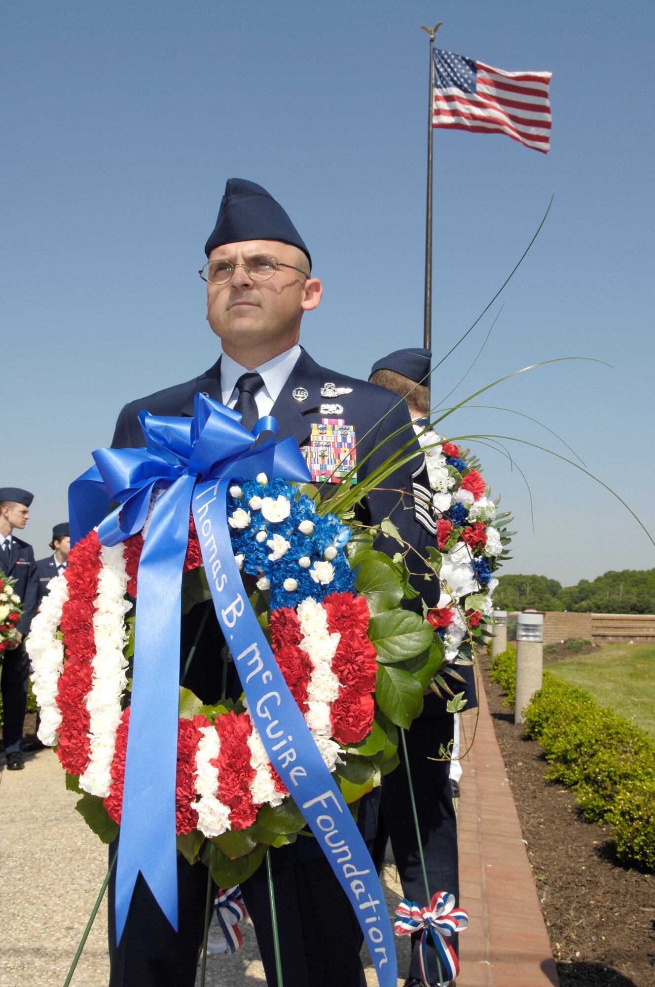 Right, Master Sgt. James McMillen, 305th Operations Support Squadron flight training unit, brings the first wreath from the Thomas B. McGuire Foundation. 