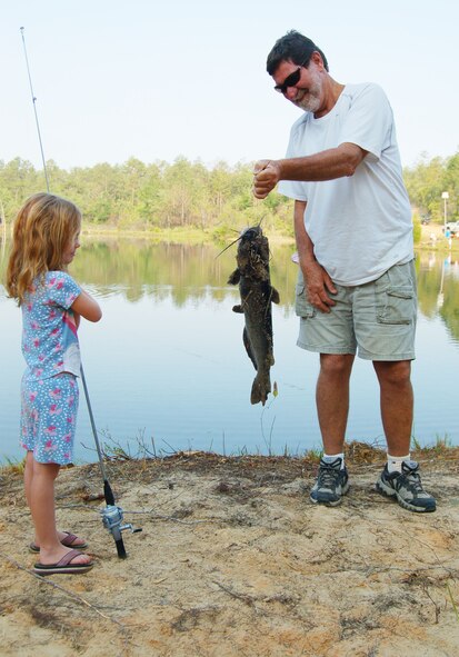 EGLIN AIR FORCE BASE, Fla. -- Rhianna Hamilton keeps a safe distance from her catch as her grandfather Steve Griner showcases her accomplishment at the Eglin Youth Fishing Rodeo May 26-27. The event was held on Prisoner Pond, an approximately five acre lake at the 6th Ranger Training Battallion compound. Members of the U.S. Fish and Wildlife Service stocked the pond with approximately 3,000 channel catfish that were provided by the USFWS Welaka National Fish Hatchery in preparation for the Rodeo event. Additionally, Jackson Guard purchased approximately 1,000 pounds of catfish that was added to the pond before the event. (U.S. Air Force photo by Jerron Barnett)