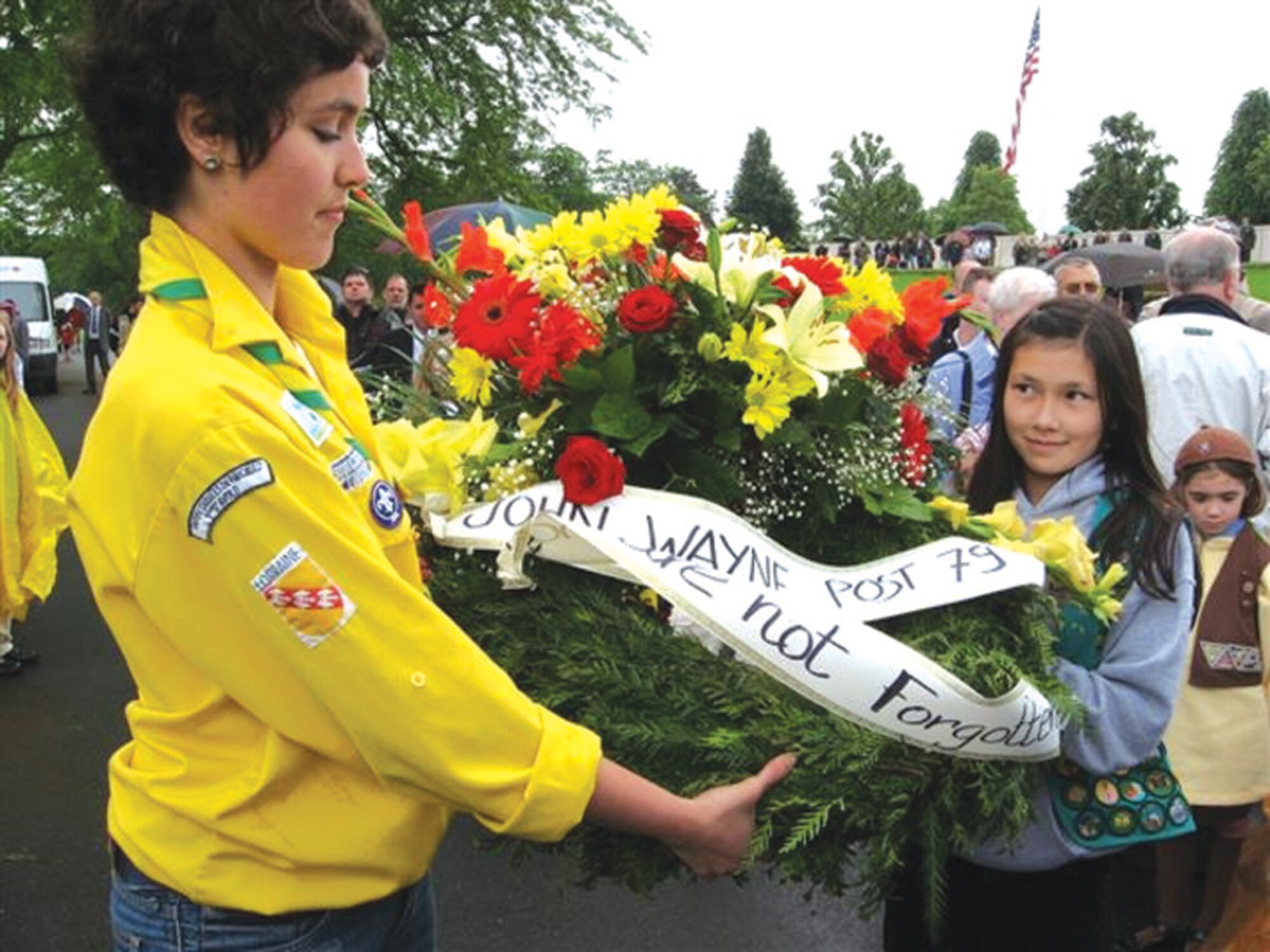 ST. AVOLD, FRANCE --  Averi Goetz (right) works with a French female guide to present a wreath during a Memorial Day ceremony at St. Avold, France. A group of 25 Scouts from Spangdahlem Air Base traveled to St. Avold, to prepare the cemetery for a Memorial Day ceremony. The girls joined 30 troops from Sembach Air Base to place flags on the more than 10,000 headstones. The girls also presented more than 40 wreaths during the ceremony. This is an annual service project for the Girls Scouts from Spangdahlem and Sembach. The girls camp at a nearby camp ground and spend the weekend work with French Guides in an effort to honor the World War II Soldiers who paid the ultimate sacrifice. (Photo by Michelle DeMers)