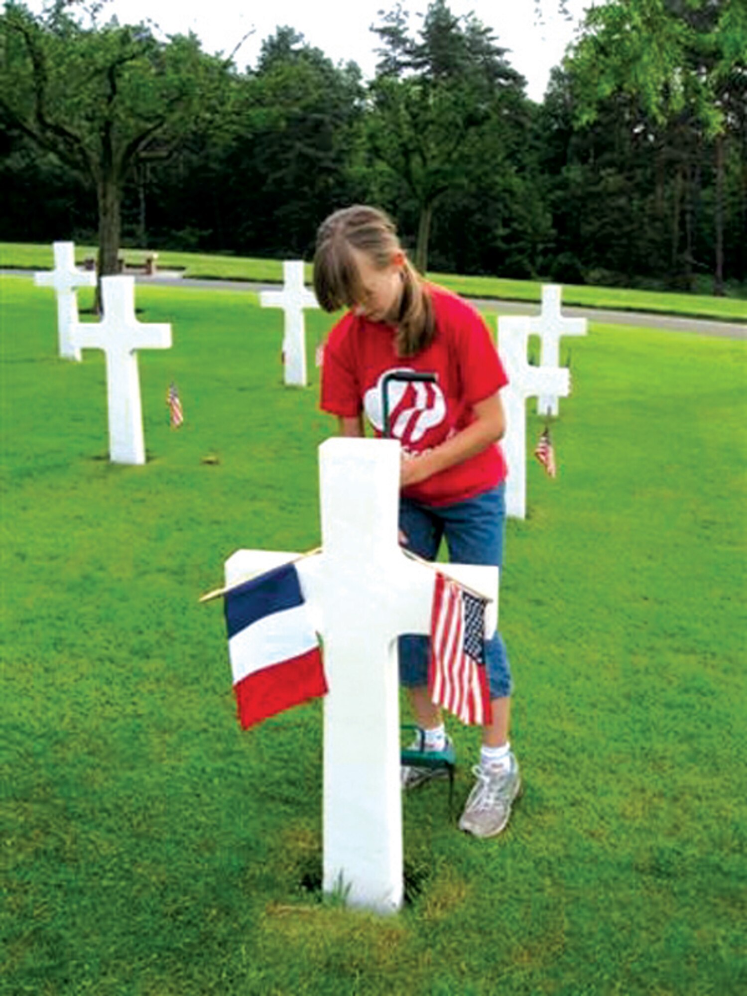 ST. AVOLD, FRANCE -- Mikayla DeMers places a U.S. and French flag on one of the more than 10,000 headstones at St. Avold, France, in preparation for a Memorial Day ceremony. A group of 25 Scouts from Spangdahlem Air Base traveled to St. Avold to prepare the cemetery for a Memorial Day ceremony. More than 20,000 flags were placed in formation. (Photo by Michelle DeMers)