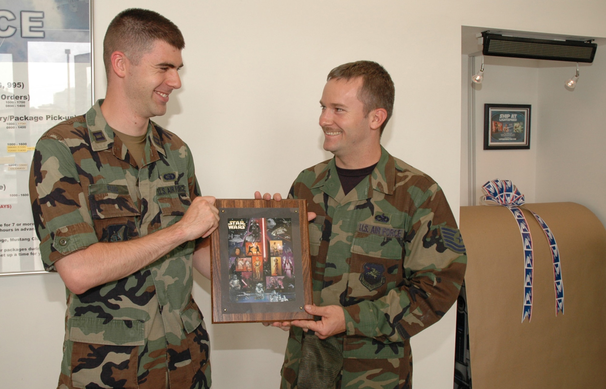 OSAN AIR BASE, Republic of Korea --  Tech. Sgt. Mark Harrell, right, receives a mounted sheet of comemrative "Star Wars" stamps from Capt. Matthew Rossi during the unveiling of the post office's new R2-D2 mail collection box. Sergeant Harrell won a drawing for the stamps, which was held in conjuction with the U.S. Postal Service's celebration of the 30th anniversary of the "Star Wars" saga. Sergeant Harrell is with the 51st Logistics Readiness Squadron and Captain Rossi is the 51st Communications Squadron postal flight commander. (U.S. Air Force photo by Staff Sgt. Benjamin Rojek) 