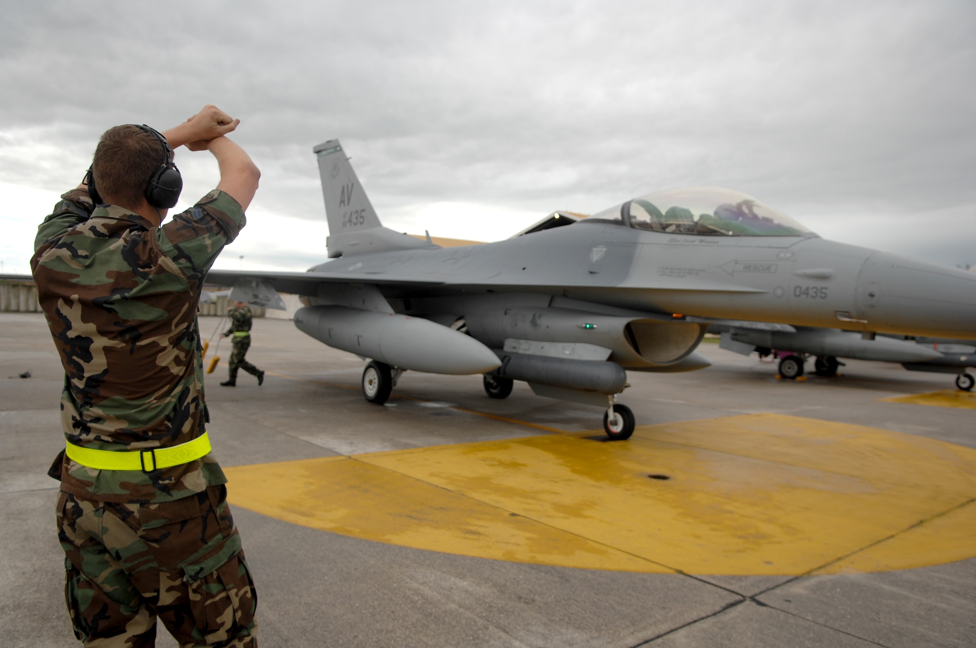 Staff Sgt. Jacob Messina, 31st Aircraft Maintenance Squadron,  marshalls an F-16 from the 555th Fighter Squadron as the squadron departs for their deployment Tuesday. (U.S. Air Force photo by Staff Sgt. Bethann Caporaletti)