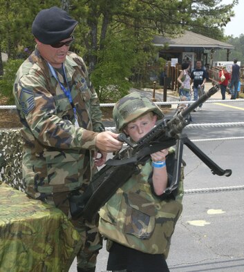 Senior Master Sgt. Rocky Epps from the 94th Security Forces Squadron assists kids with trying on protective gear and the M-240 machine gun while manning a security forces display at Stone Mountain Park during a Heritage To Horizons event there Memorial Day Weekend. The Air Force 60th Anniversary was a highlight of the weekend. (U.S. Air Force photo/Don Peek)