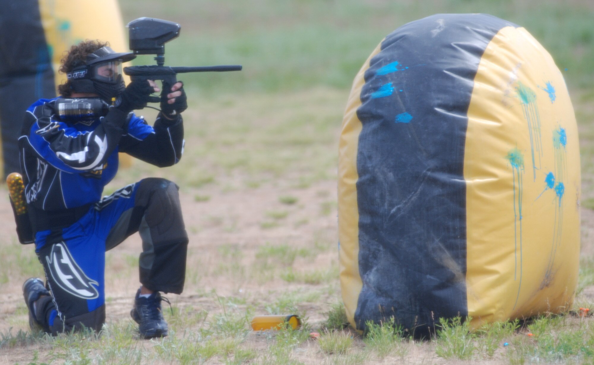 FAIRCHILD AIR FORCE BASE, Wash. -- Craig McMullan, son of Chief Master Sgt. Daniel McMullan, 92nd Operations Group superintendent, takes a firing position behind an obstacle while playing speedball at the sports range here May 26. The speedball field is open every Saturday, 10 a.m. – 4 p.m., and has rental equipment available for anyone who wants to play. (U.S. Air Force photo/Tech. Sgt. Larry Carpenter) 