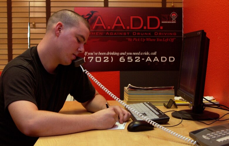 Airman Nicholas Frazier, a finance technician with 99th Comptroller Squadron, demonstrates Airmen Against Drunk Driving call-taking procedure. In order to pick a person up volunteers need to write down the caller’s location and destination, the type of car they are driving, clothes they are wearing, a cell phone number and a name. (Air Force photo/Airman 1st Class Oleksandra Manko)