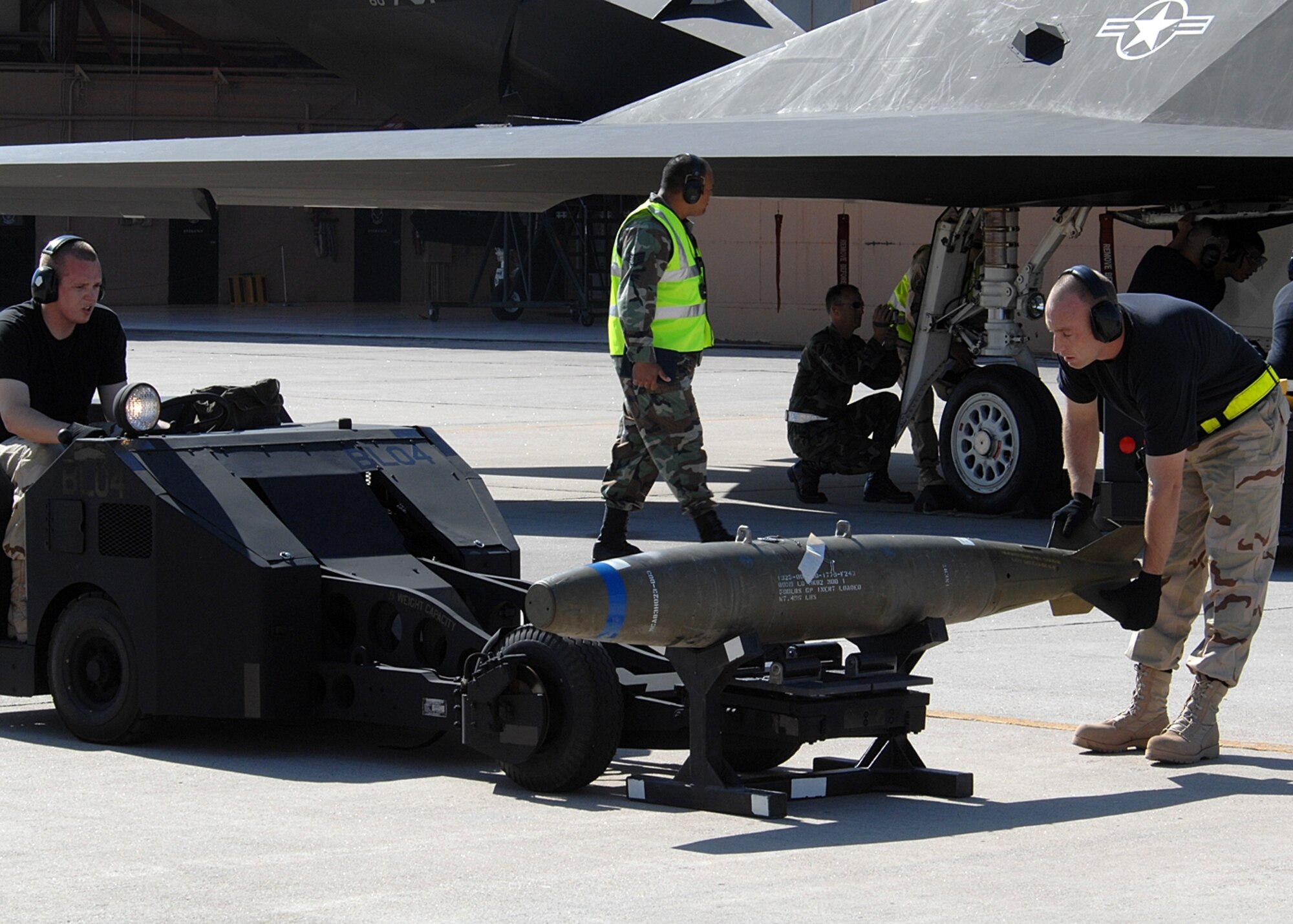 A Holloman weapons load crew team uses one of the black jammers to place the bomb onto the bomb rack of an F-117A Nighthawk during a weapons loading demonstration showcasing what the crews will do at the Pioneer Air Festival at Cannon AFB June 7-8. (U.S. Air Force photo/ Airman 1st Class John Strong)