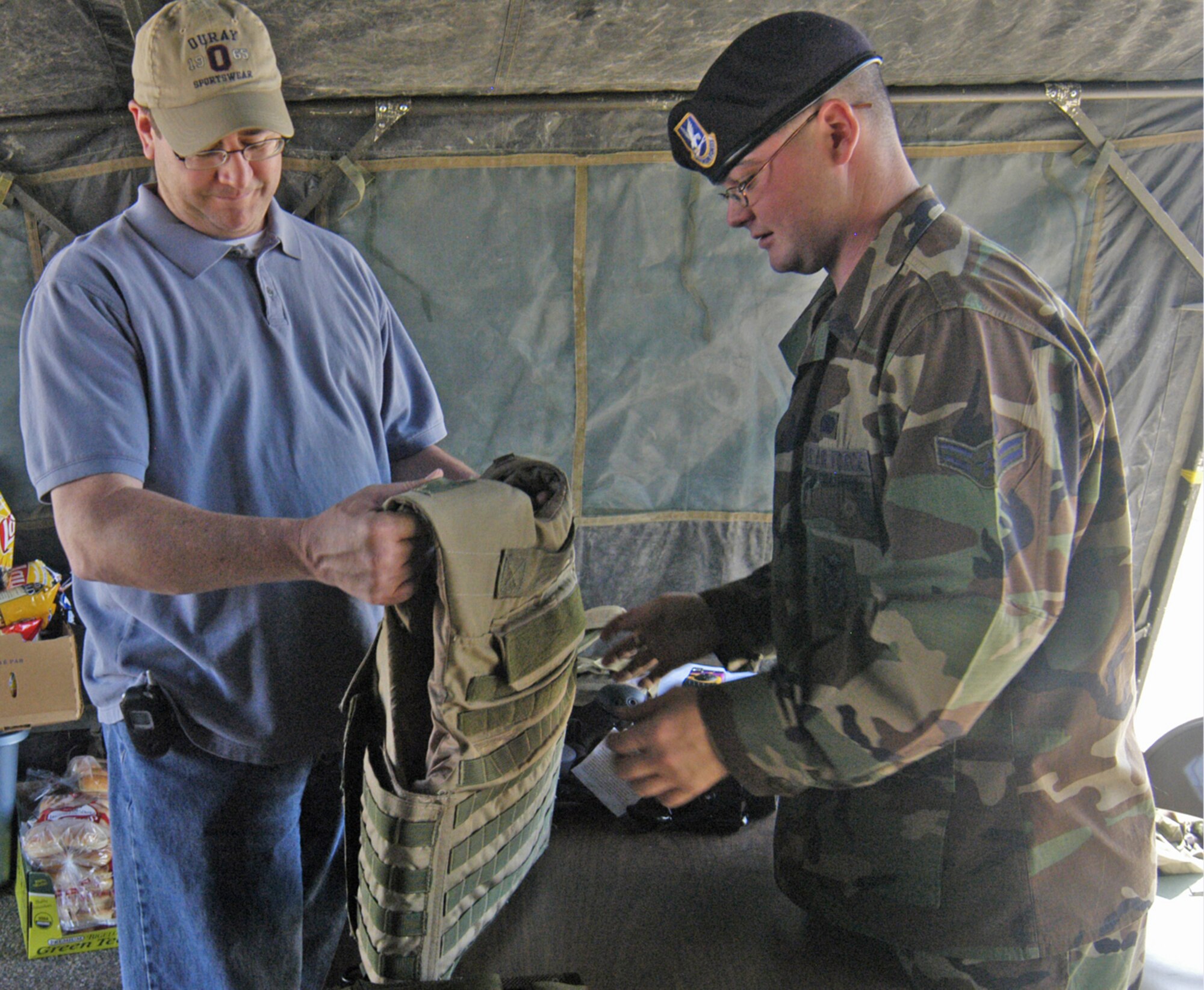 Airman 1st Class Jeffrey Howard, 90th Security Forces Squadron, explains the details of the M-TAC 300-series ballistic vest used for high speed tactical teams and military special forces to a local man. 