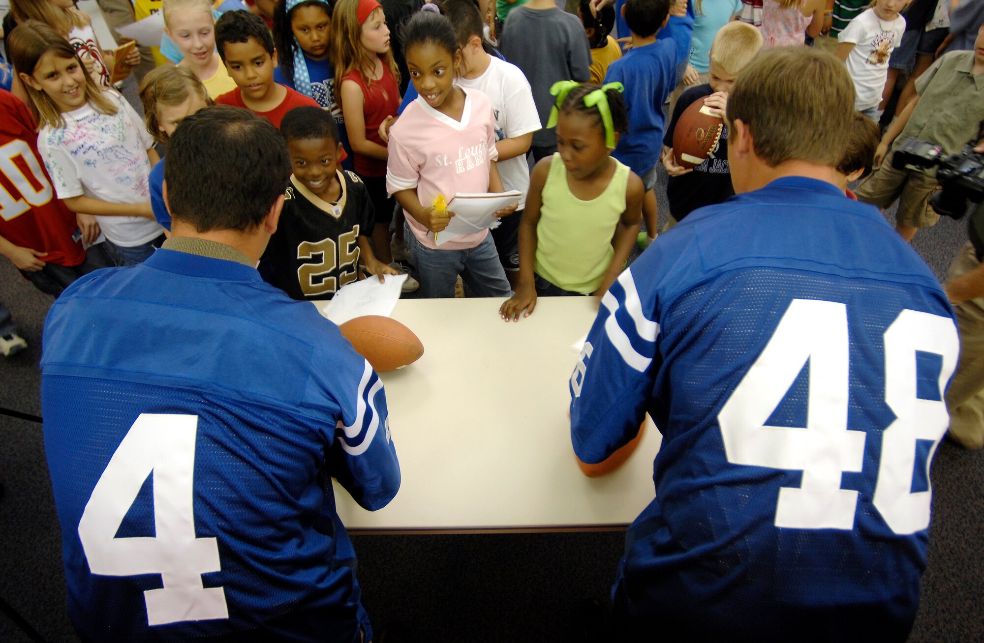Indianapolis Colts kicker Adam Vinatieri (left) and long snapper Justin Snow sign autographs for students at Randolph Elementary School on Randolph Air Force Base, Texas, June 1. Colts team members spent the day visiting with base personnel and school children, enhancing the already strong relationship between the team and the Air Force.  (U.S. Air Force photo/Staff Sgt. Brian Ferguson)
