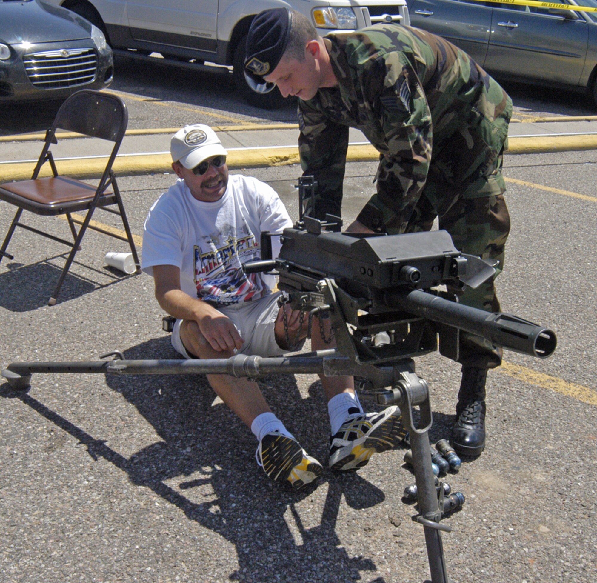 Staff Sgt. Greg Carroll, 790th Missile Security Forces Squadron, demonstrates the workings of the Mk-19 40mm machine gun to Rob Marwick, a local Cheyenne resident, outside Frontier Mall May 19.