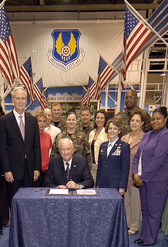 Secretary of the Air Force Michael Wynne (seated) was on hand at Tinker Air Force Base, Okla., May 22 to sign a memorandum of agreement between the Defense Advanced Research Projects Agency and Air Force Materiel Command that will enhance F100 and F110 turbine engines. Also present for the signing are Lt. Gen. Terry Gabreski, Air Force Materiel Command vice commander (center right, in service dress uniform) and members from the Oklahoma City Air Logistics Center. (Air Force photo by Margo Wright)

