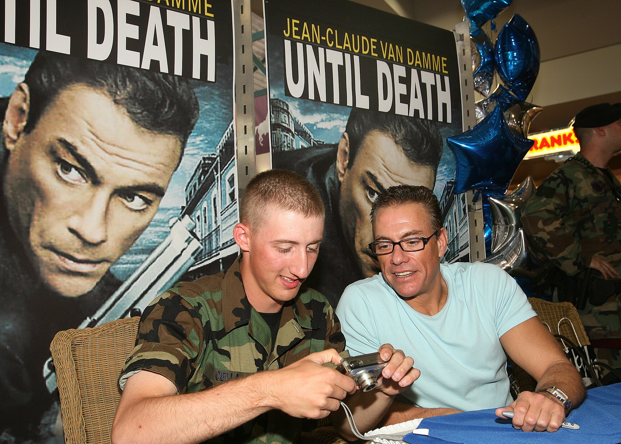 Airman Basic Mathew Cella shows actor Jean-Claude Van Damme a digital image from his camera after the two posed for photos June 2 at the base exchange at Lackland Air Force Base, Texas. Mr. Van Damme signed autographs and posed for photos with base members. Airman Cella is going through technical training in the security forces career field with the 343rd Training Squadron at Lackland AFB. (U.S. Air Force photo/Robbin Cresswell) 
