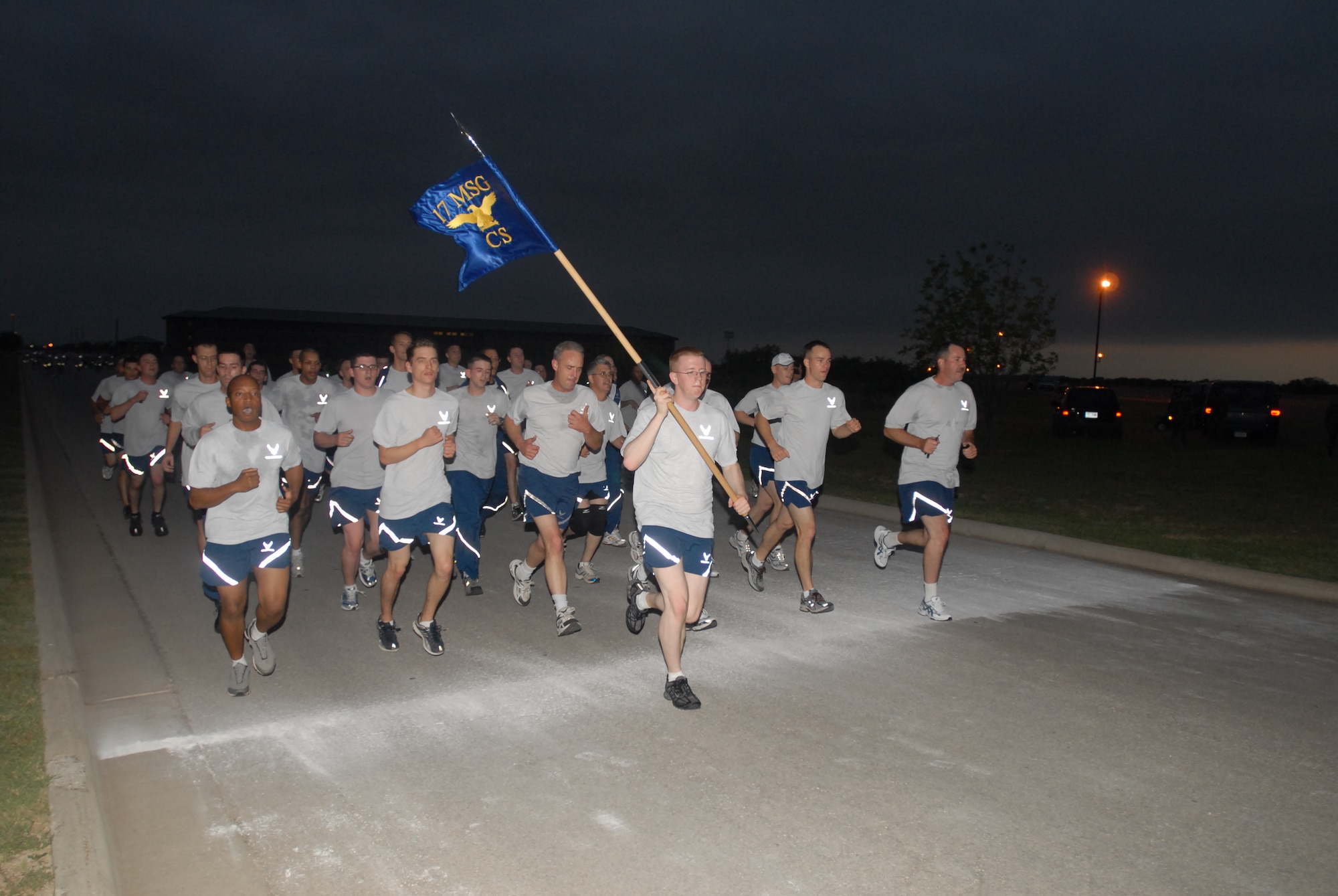 Then-Senior Airman John Sanders holds the 17th Communications Squadron guidon high as the 17 CS takes part in this year’s first 17th Training Wing Warrior Run May 25 on base.The 17 CS was the first unit formation to cross the finish line. The warrior run kicked off this year’s Goodfellow Safety Day activities.  All running participants demonstrated good safety habits by doing some stretching exercises before the 2.2-mile-run.  Participants also performed stretching exercises as part of the “cool down” period after the run. (U.S. Air Force photo by Staff Sgt. John Barton).