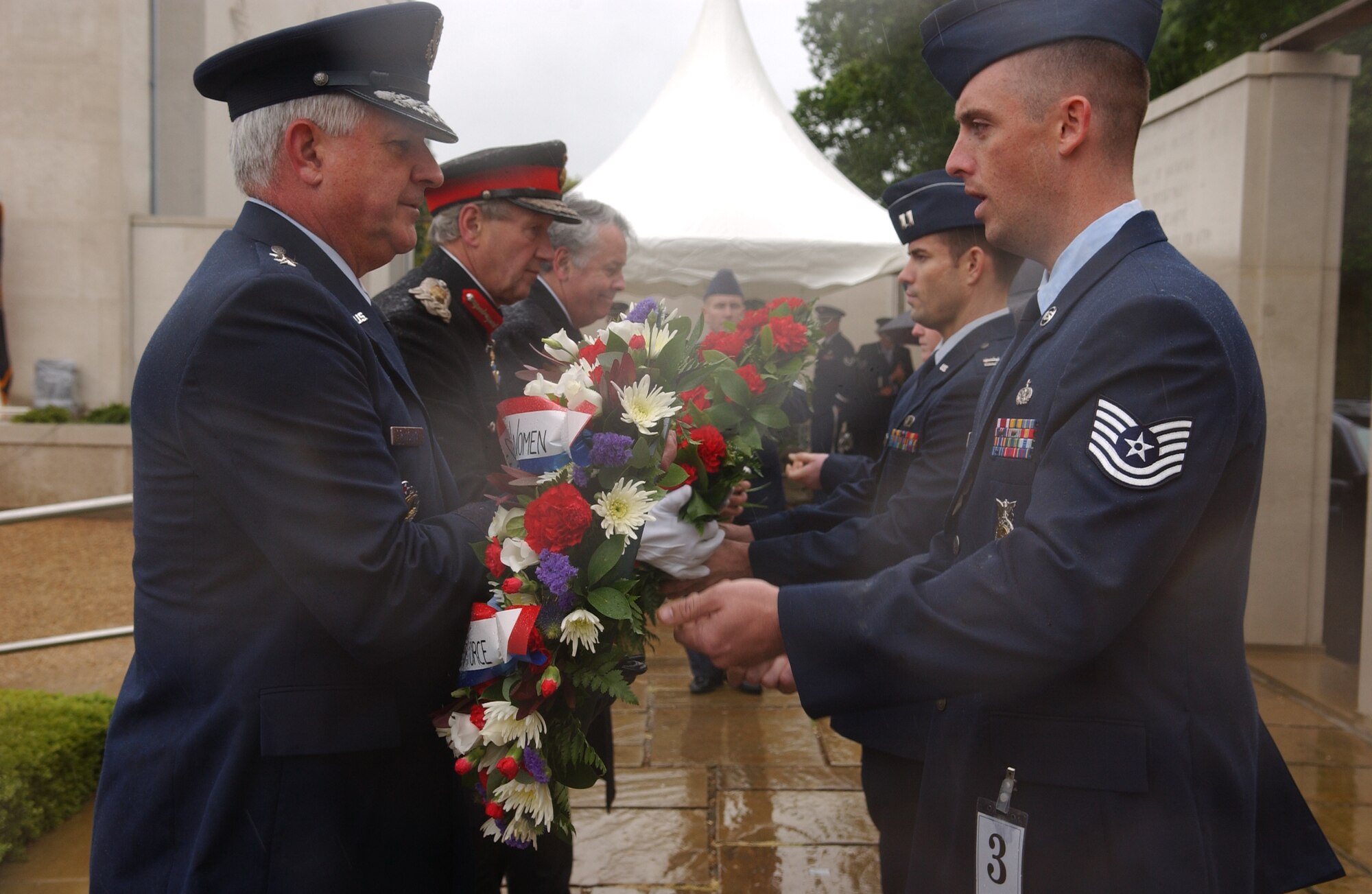 Tech. Sgt. Joshua Trundle, 100th Civil Engineering Squadron, hands Maj. Gen. Paul Fletcher, 3rd Air Force commander, a wreath to honor the 5,126 Americans whose names are listed on a memorial wall at the Madingley World War II American Cemetery, in Cambridge, England, May 28, 2007. (Air Force photo by Tech. Sgt. Tracy L. DeMarco)